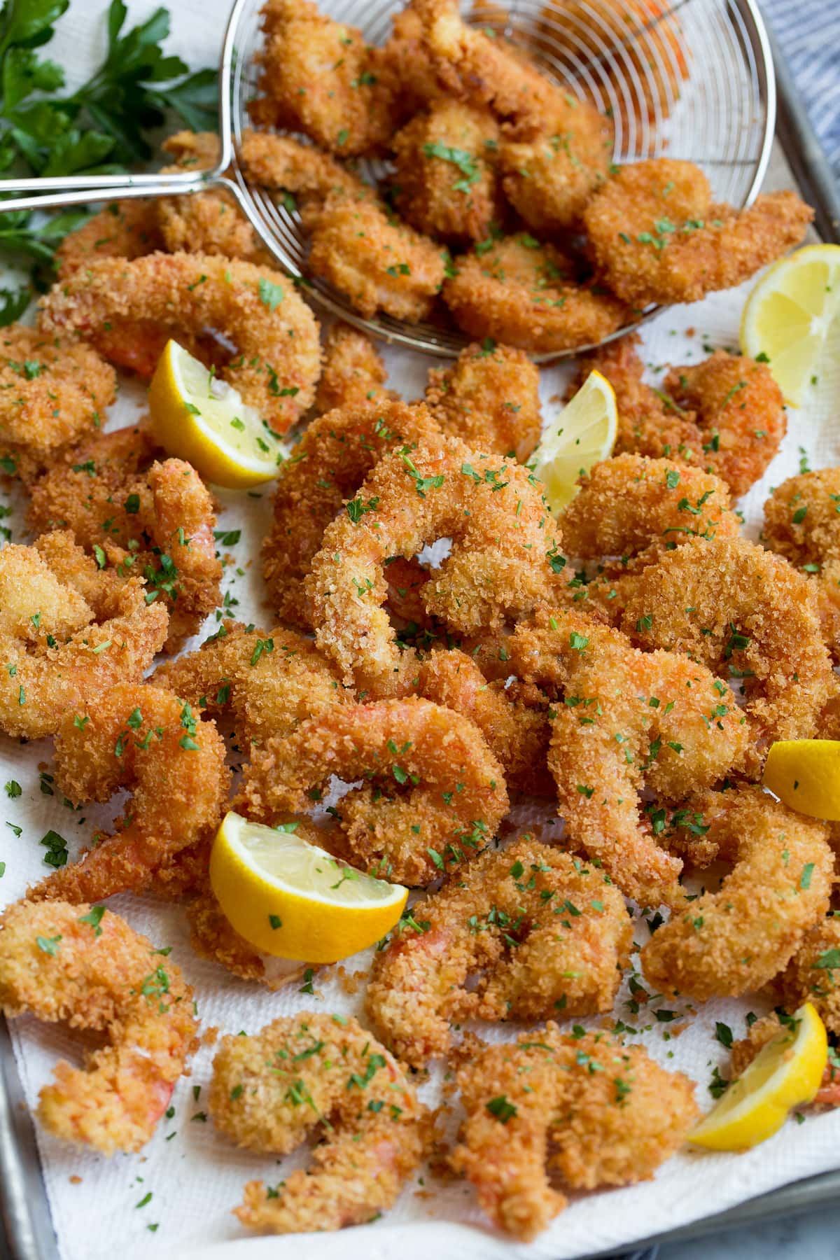 Fried Shrimp Close up photo of shrimp piled on paper towel lined sheet pan.