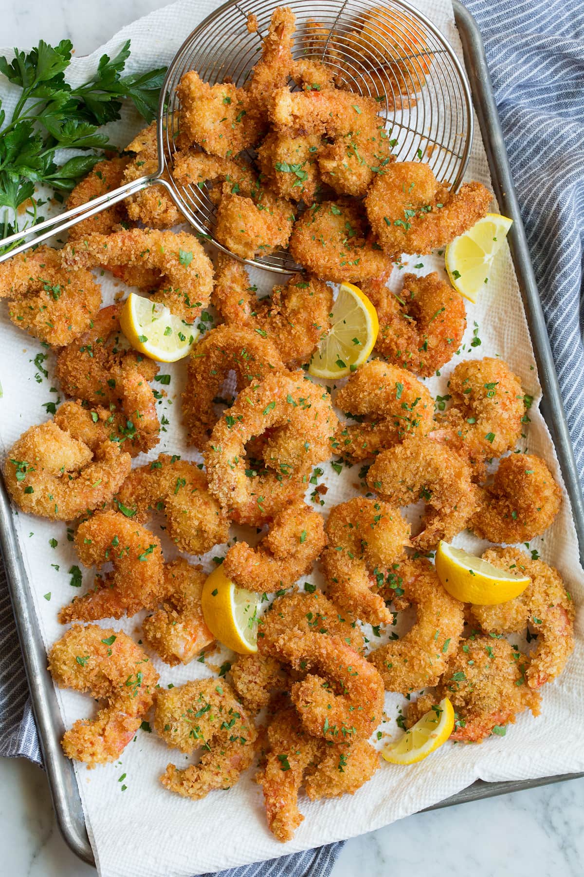 Fried Shrimp Overhead photo of fried shrimp layered on paper towel lined baking sheet.