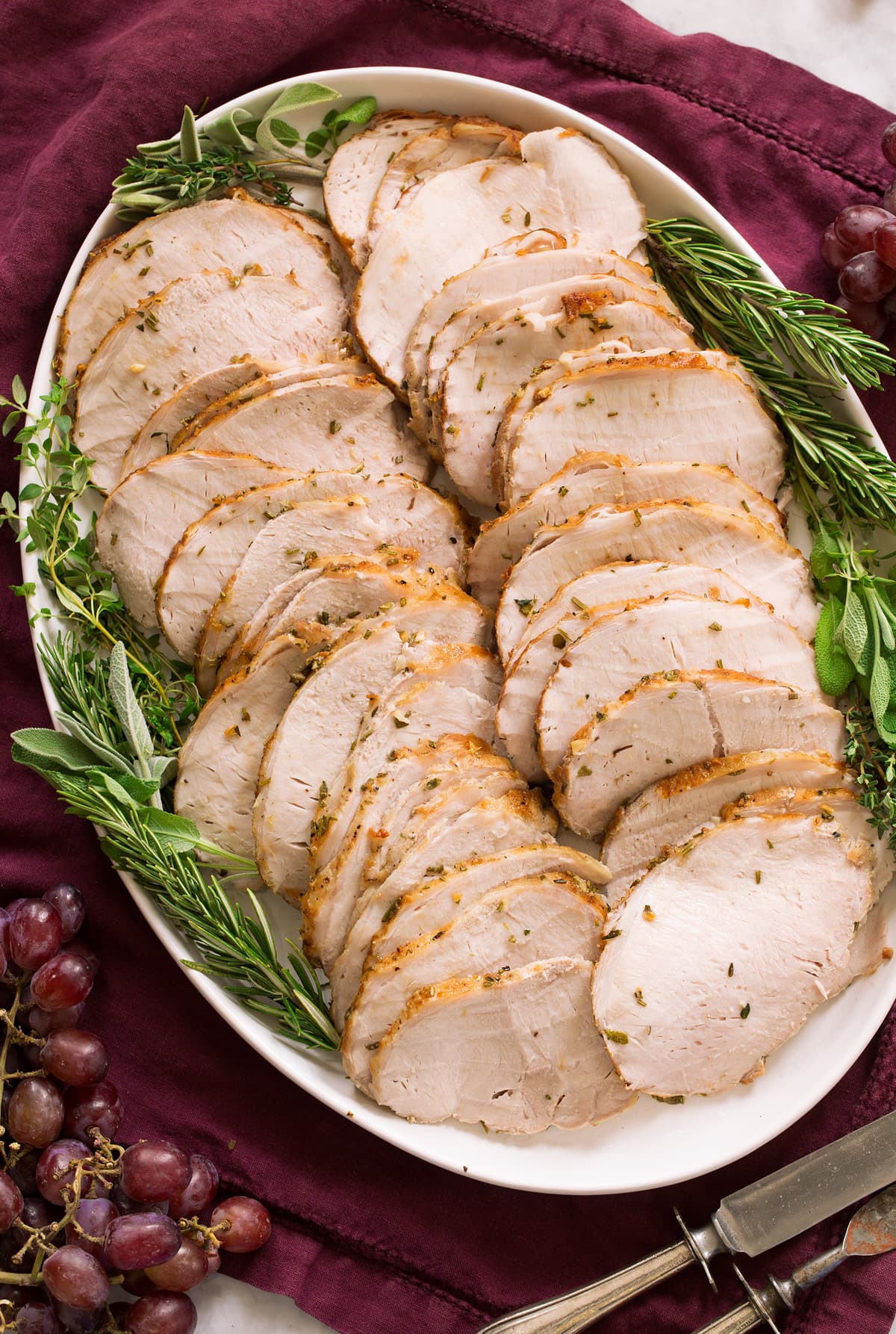 Pork Loin Pork loin shown cooked and thinly sliced on a white oval serving platter over a purple cloth.