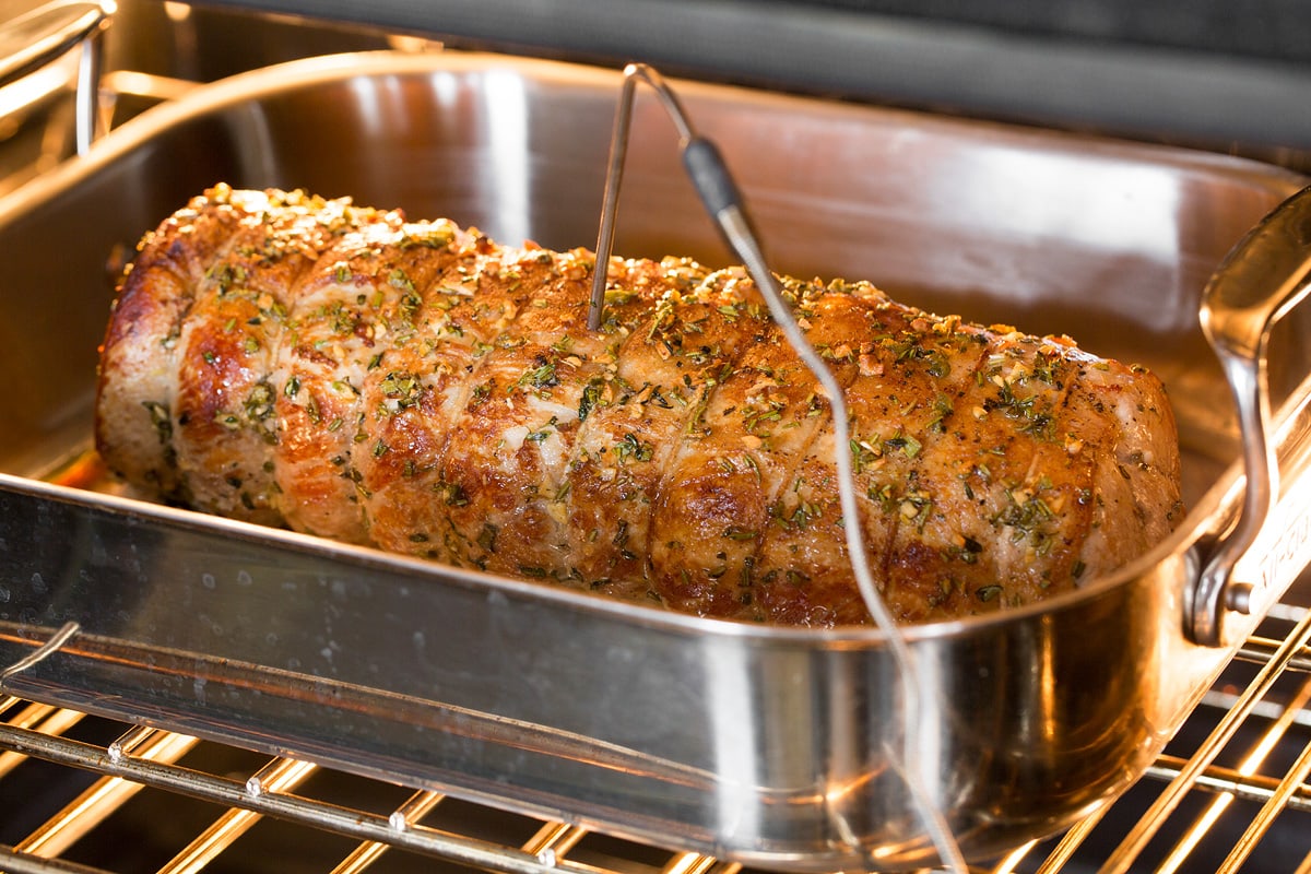 Pork Loin Roast Pork loin shown in roasting pan in the oven with an oven probe thermometer inserted into center.