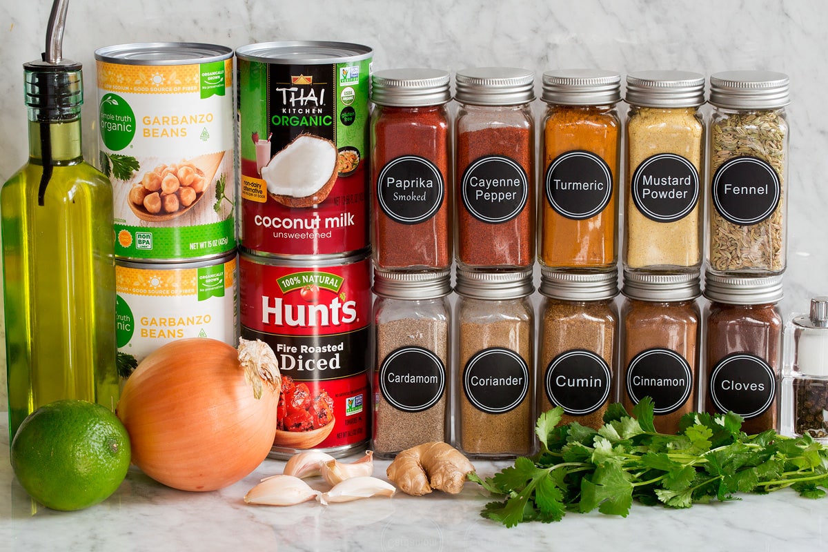 Chickpea Curry Photo of ingredients used to make chickpea curry. Includes chickpeas, coconut milk, canned fire roasted tomatoes, onion, garlic, ginger, cilantro, lime, paprika, cumin, coriander, cayenne pepper, fennel seed, mustard powder, turmeric, cinnamon, cardamom, cloves, salt and pepper.