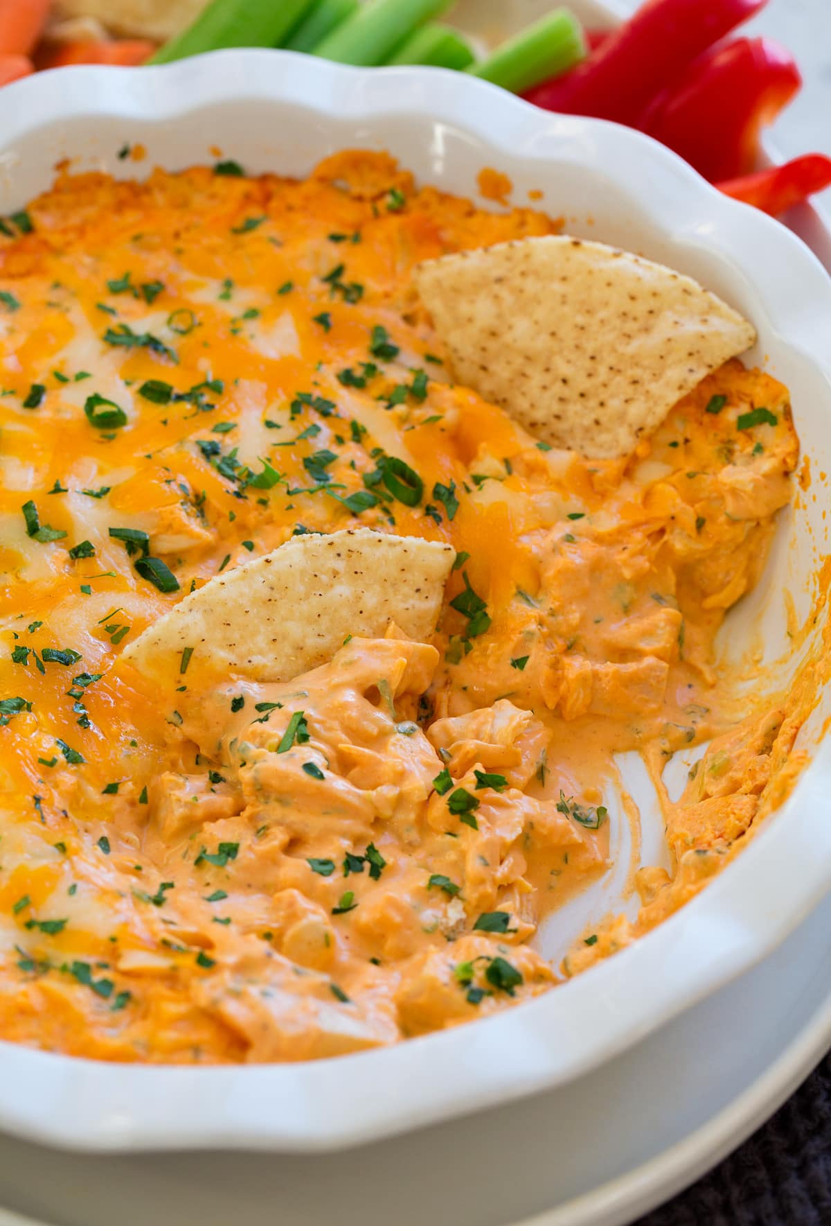 Buffalo Chicken Dip Buffalo chicken dip in a ceramic white pie dish. Shown with tortilla chips dipped in.