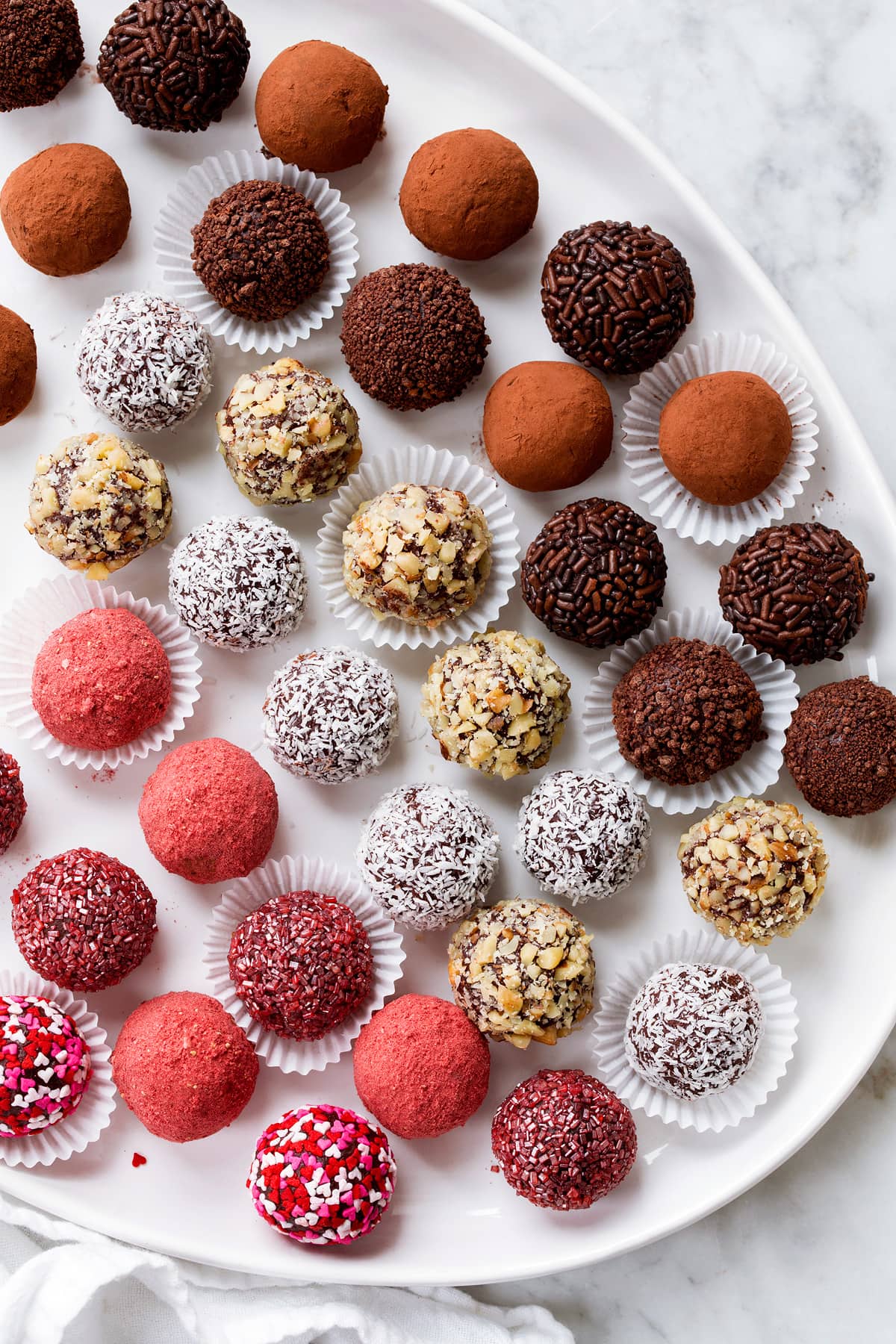Chocolate Truffles Rows of chocolate truffles coated in different toppings shown on a white oval serving platter.