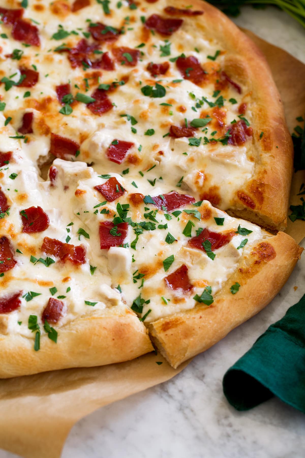 Chicken Alfredo Pizza Side angle of sliced chicken alfredo pizza.