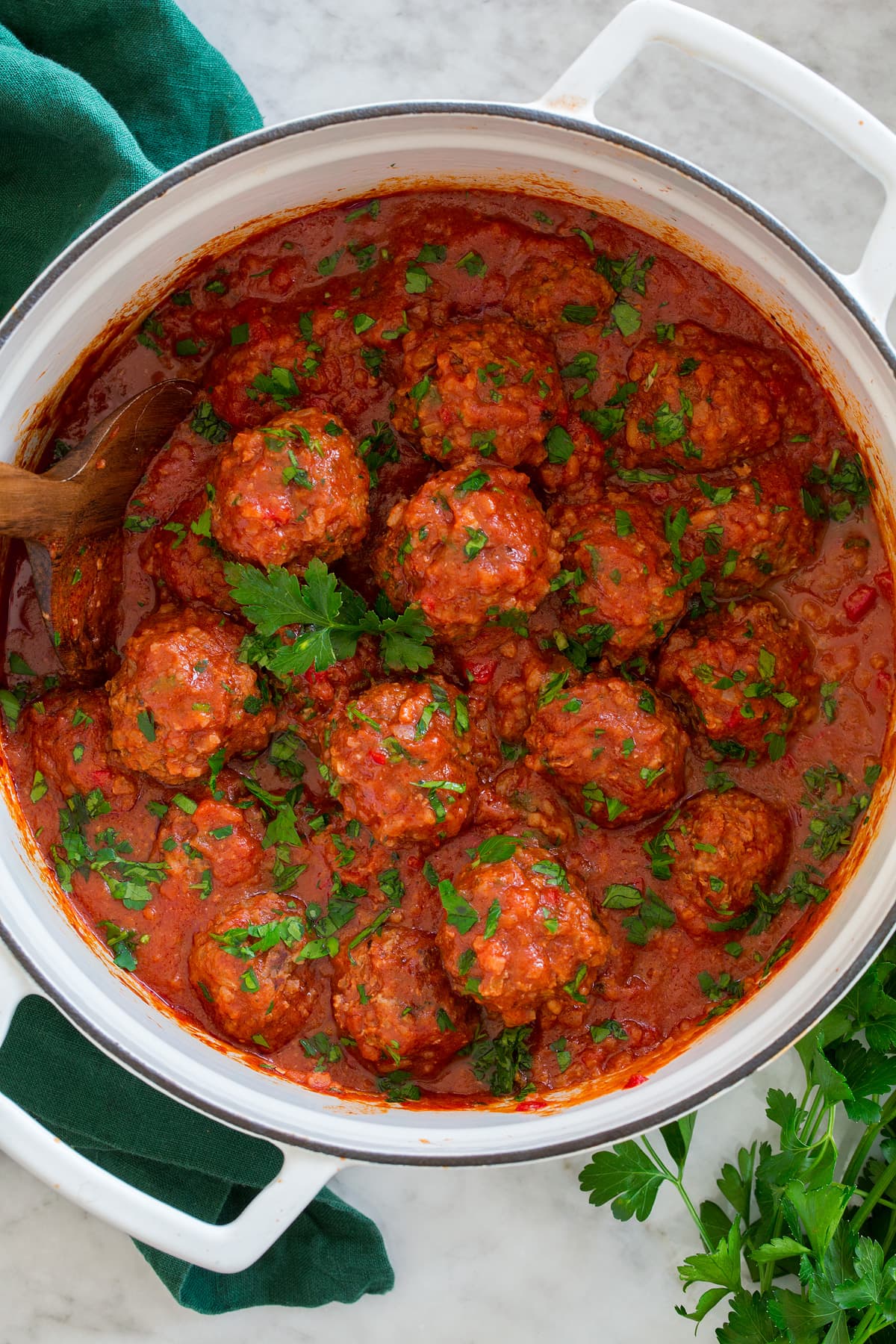 Porcupine Meatballs Overhead photo of Porcupine Meatballs in tomato sauce in a large white pot set over a marble surface with a green cloth to the side.