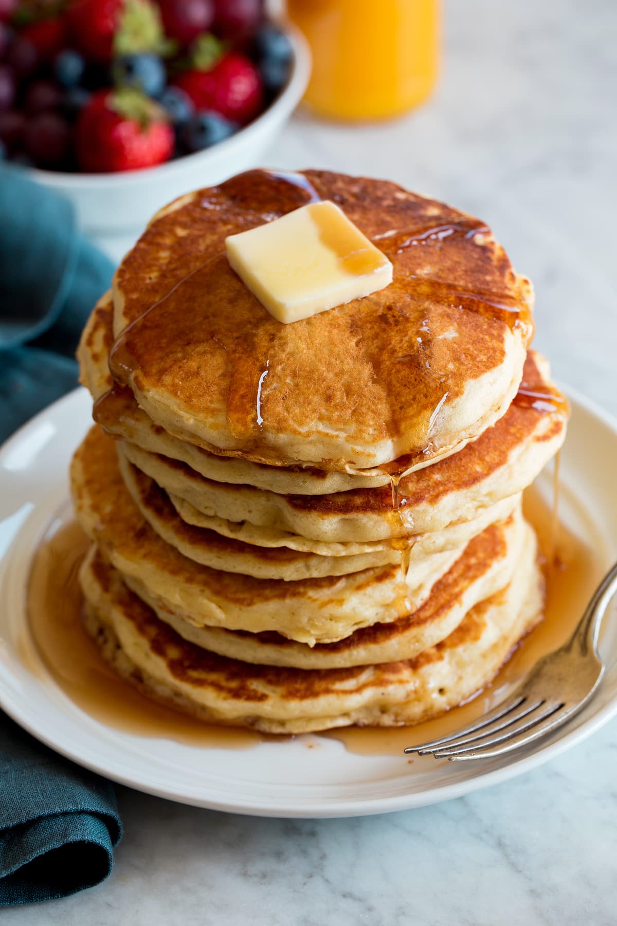 Homemade Pancakes Stack of homemade pancakes on a white plate. Pancakes are topped with maple syrup and butter.