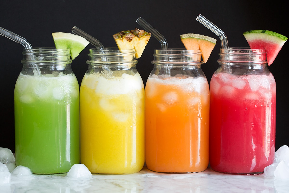 Aqua Fresca Photo: Four kinds of fruit aqua fresca shown in glass jars with glass straws and fruit wedge garnish.