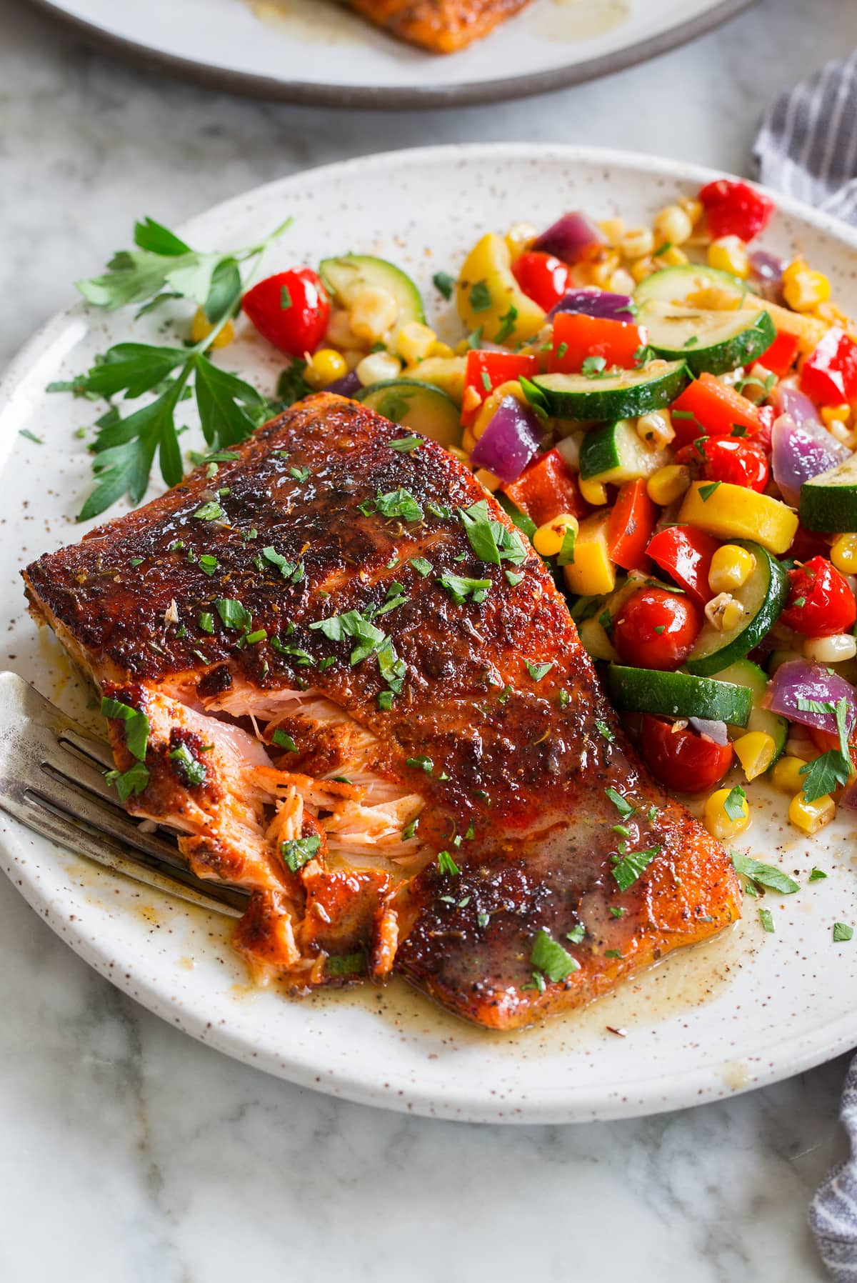 Blackened Salmon Close up photo of blackened salmon with buttery honey lime sauce. Sautéed vegetables are shown to the side as a serving suggestion.