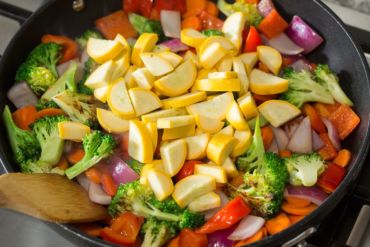 Sautéed Vegetables Photo: Adding squash to vegetable mixture in skillet.