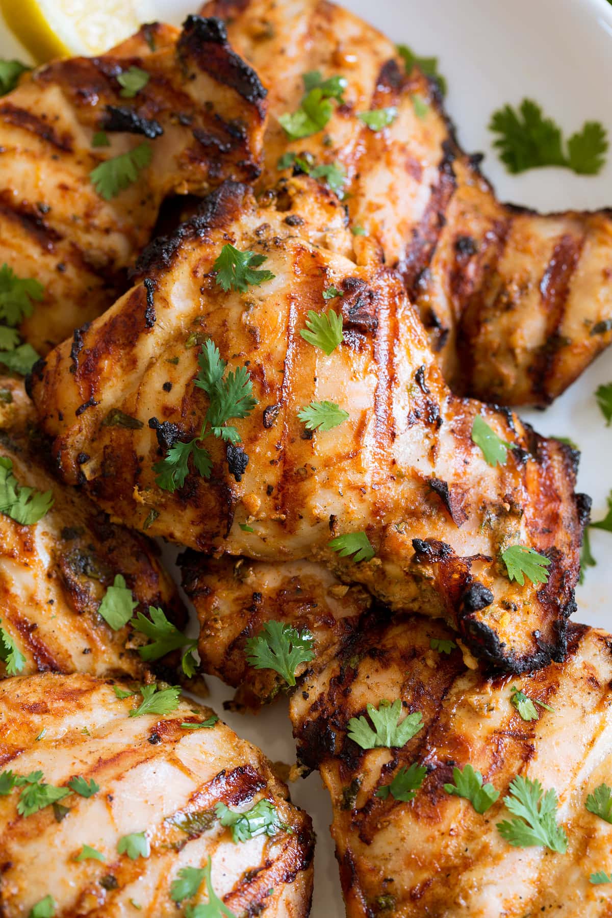Greek Yogurt Marinated Grilled Chicken Close up photo of grilled chicken thighs with yogurt marinade. Chicken is garnished with cilantro.