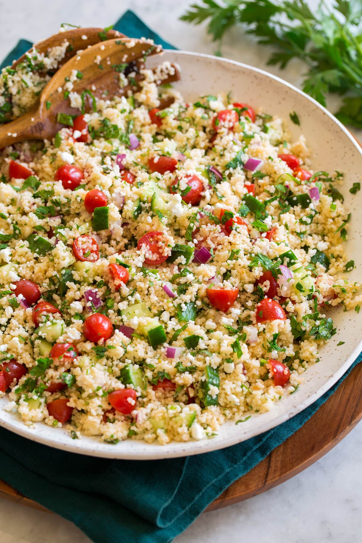 Couscous Salad Couscous salad with cucumbers, tomatoes, and herbs shown in a white bowl from the side.