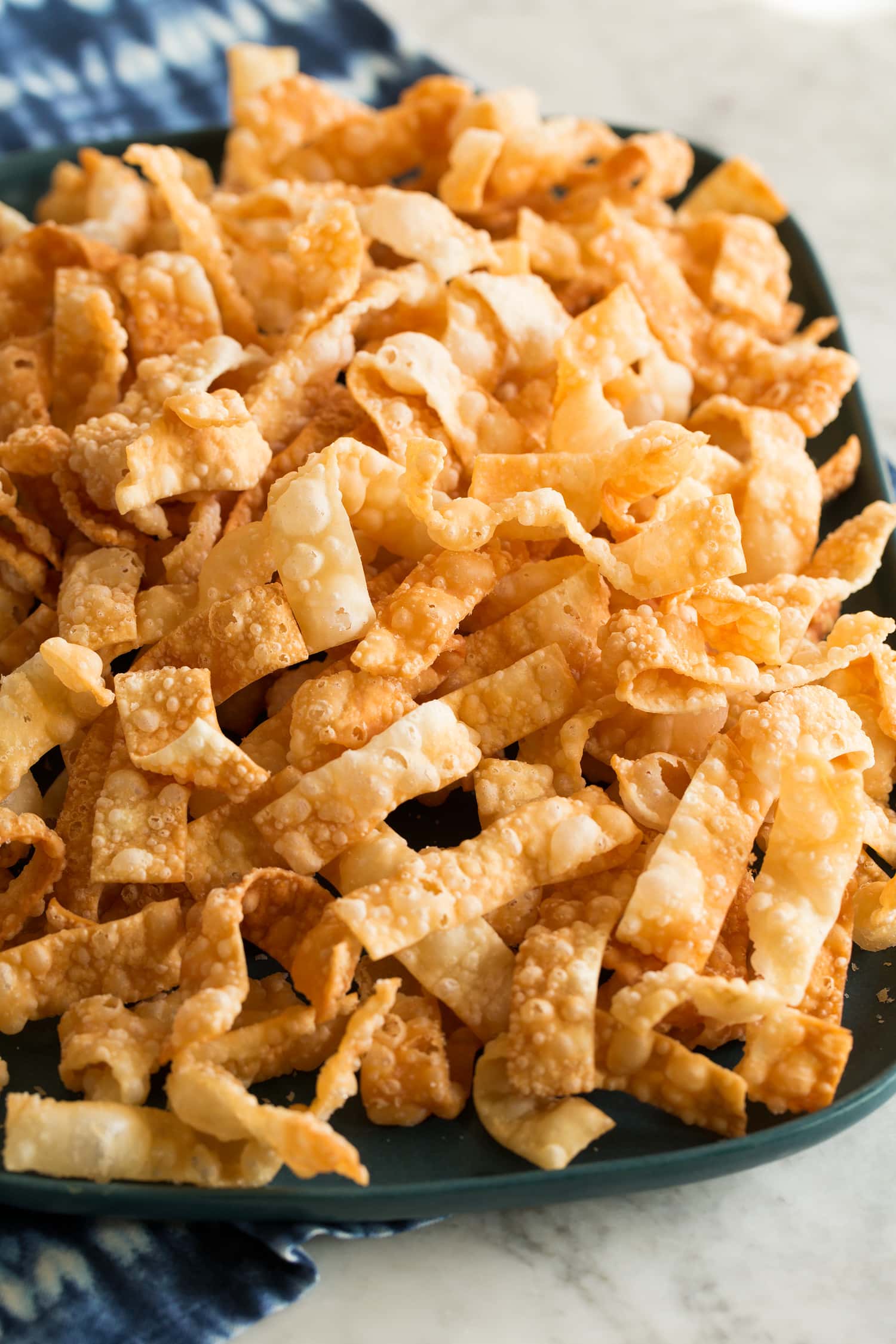 Fried Wonton Strips Fried wonton strips piled together on a blue serving platter.