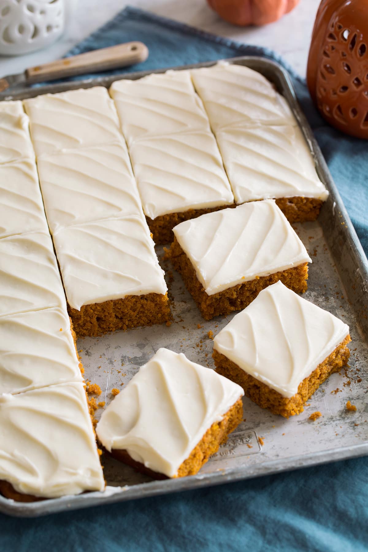 Pumpkin Bars Pumpkin bars with cream cheese frosting cut into squares and shown on a metal sheet pan.