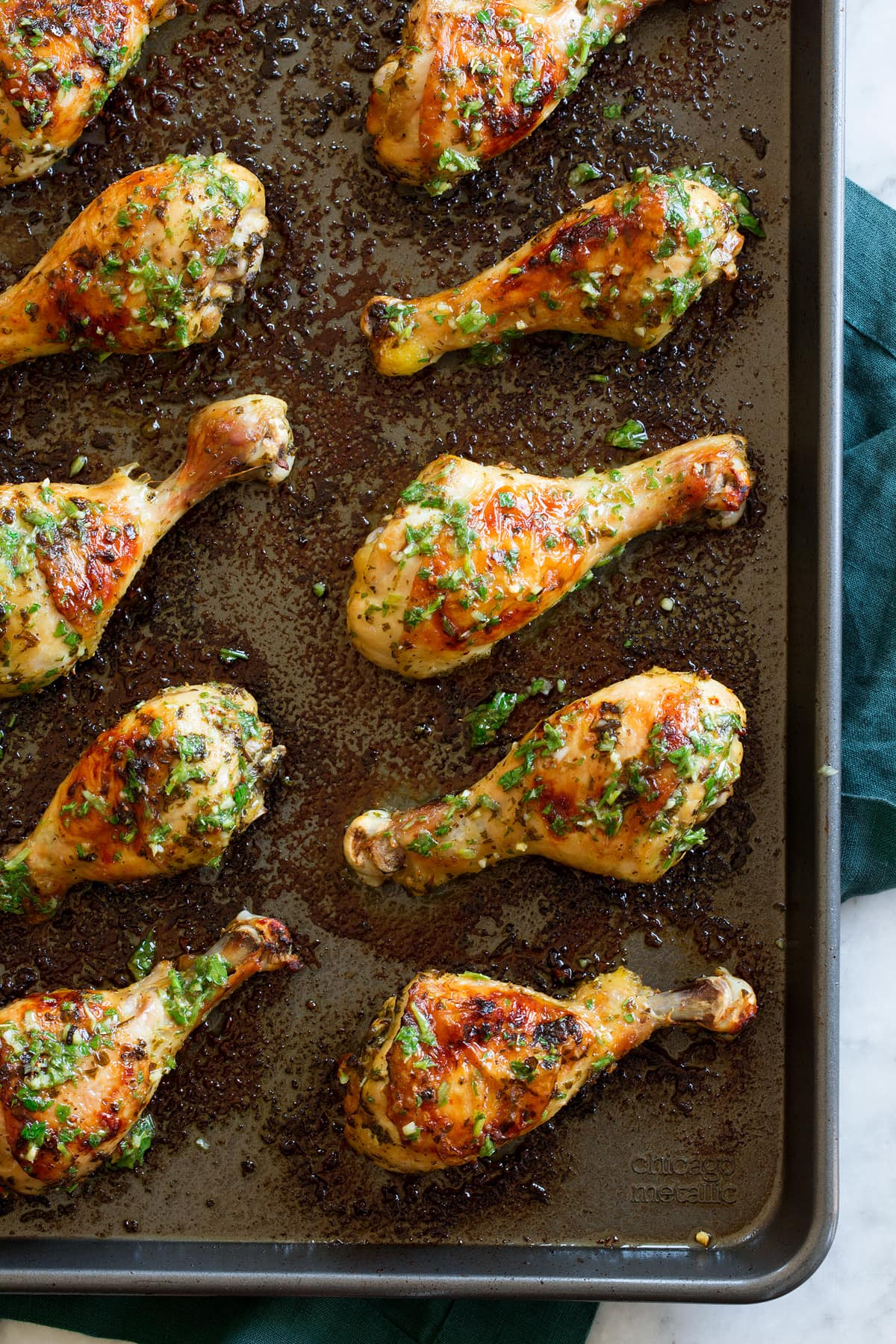 Baked Chicken Legs Chicken legs shown on baking sheet covered with chimichurri style sauce.