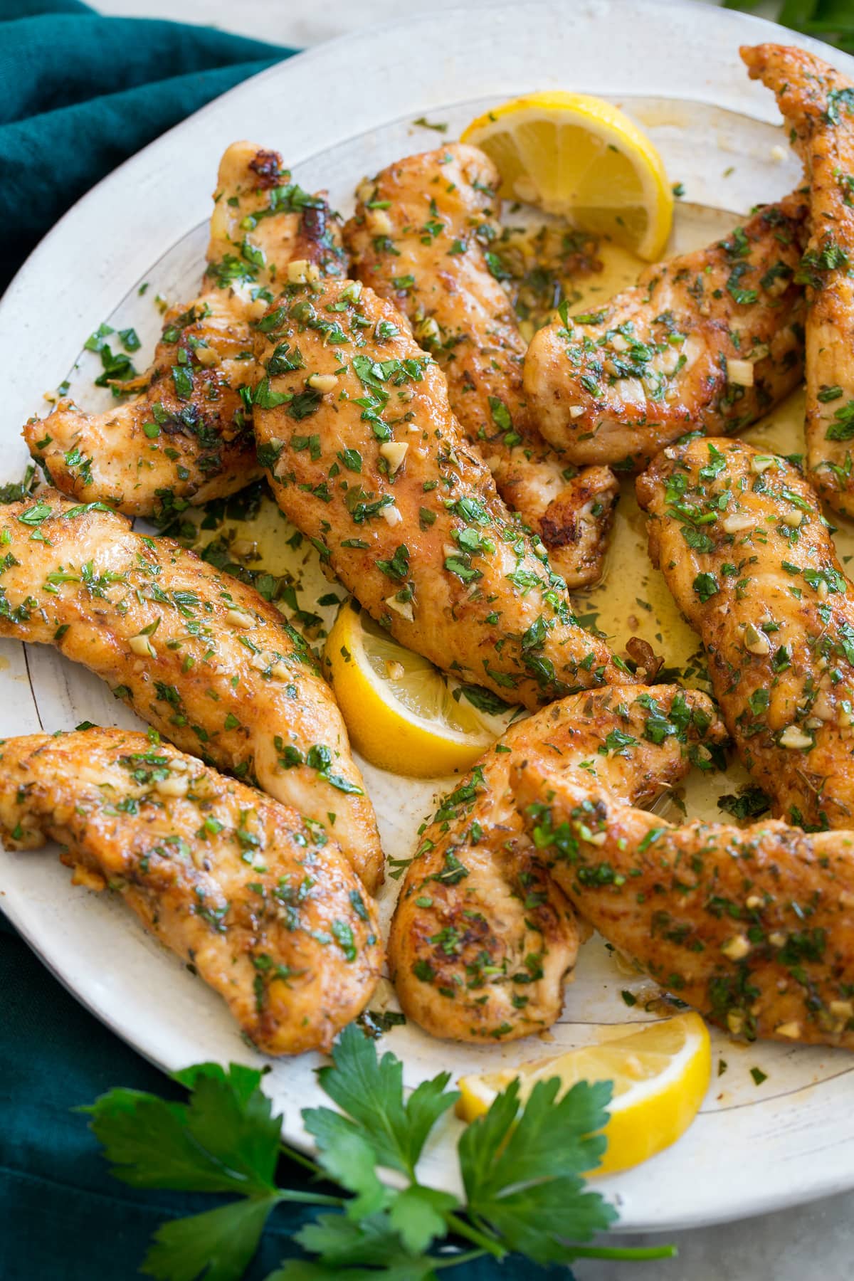 Chicken Tenders Seared chicken tenders with butter and lemon shown close up.