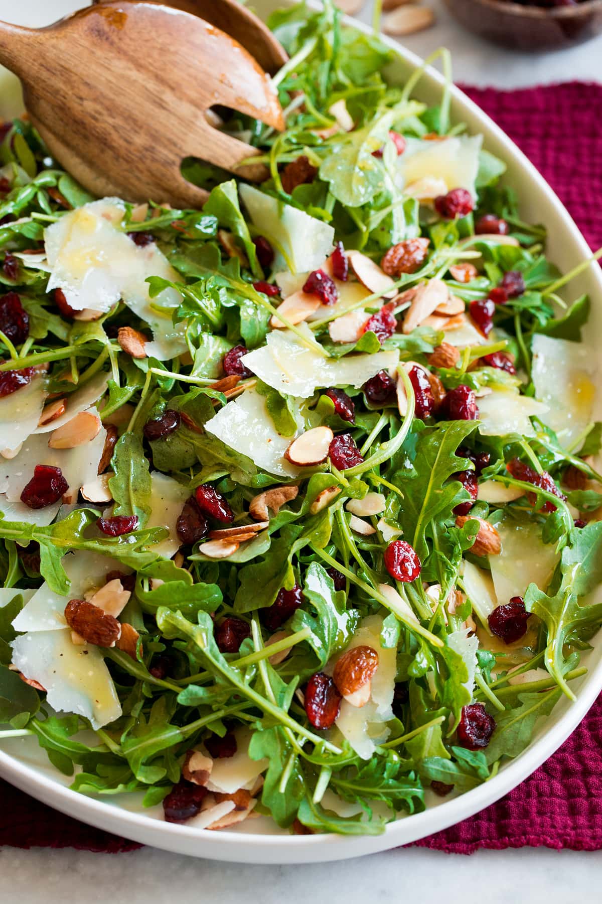 Arugula Salad Arugula salad shown with salad serving spoons scooping salad.