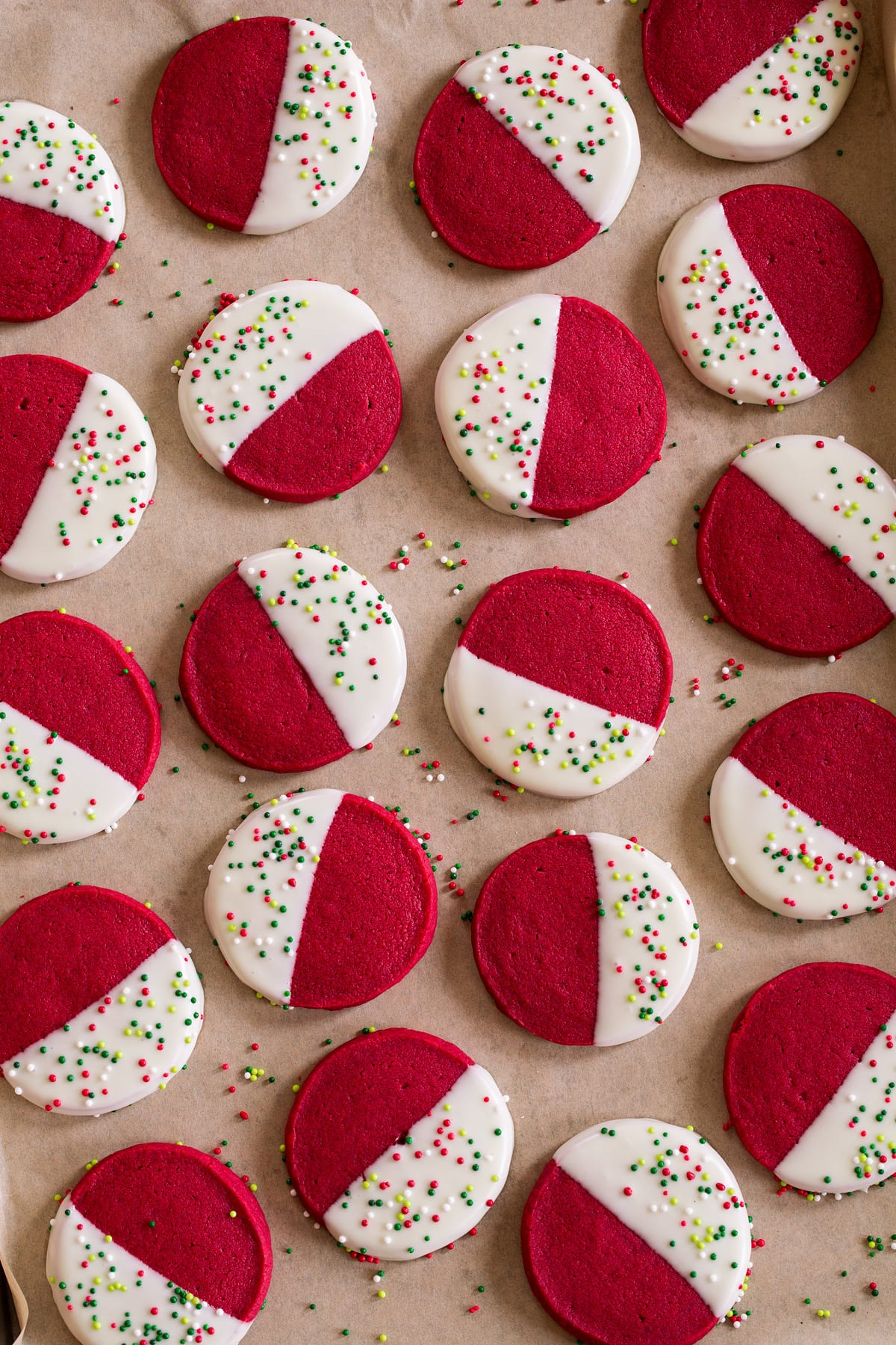 Red Velvet Shortbread Christmas Cookies Red velvet shortbread shown dipped in white chocolate and resting on parchment paper.