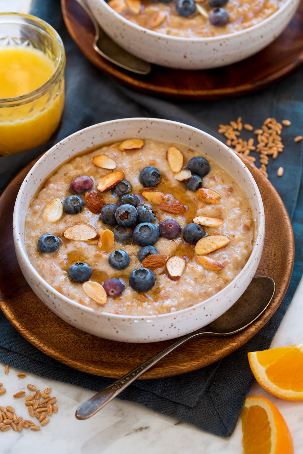 Multigrain Porridge Multigrain porridge made with steel cut oats, farro and amaranth. It is shown served with fresh blueberries, sliced almond and maple syrup.