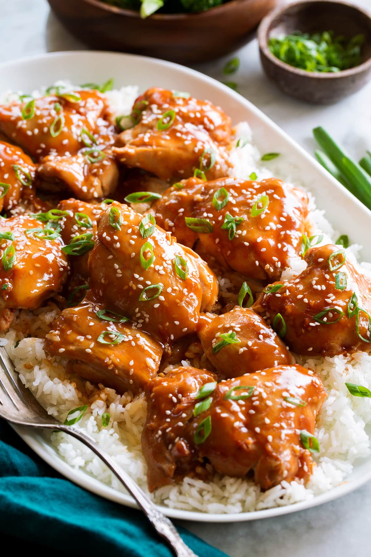 Slow Cooker Chicken Thighs Close up image of saucy chicken thighs with green onions and sesame seeds.