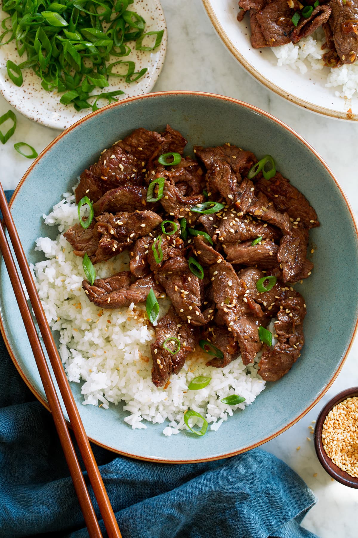 Bulgogi Overhead photo of beef bulgogi served with white rice in a light blue bowl with chopsticks to the side.