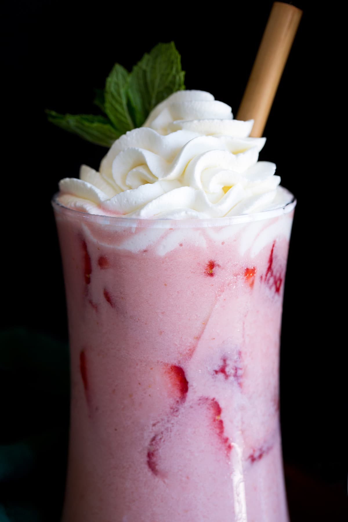 Pink Drink Recipe Close up photo of pink drink in a glass with a wooden straw.