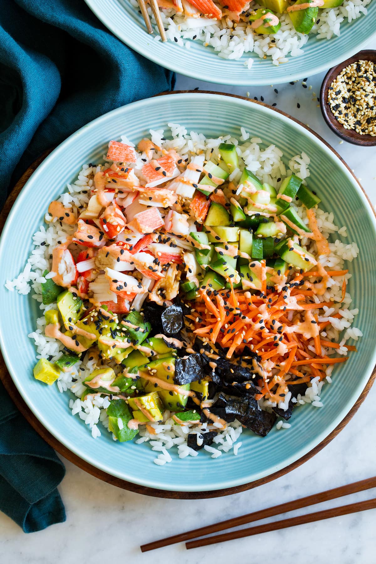 California Roll Sushi Bowls Close up photo of sushi bowl with crab, carrots, cucumber, avocado, nori, pickled ginger, and rice.
