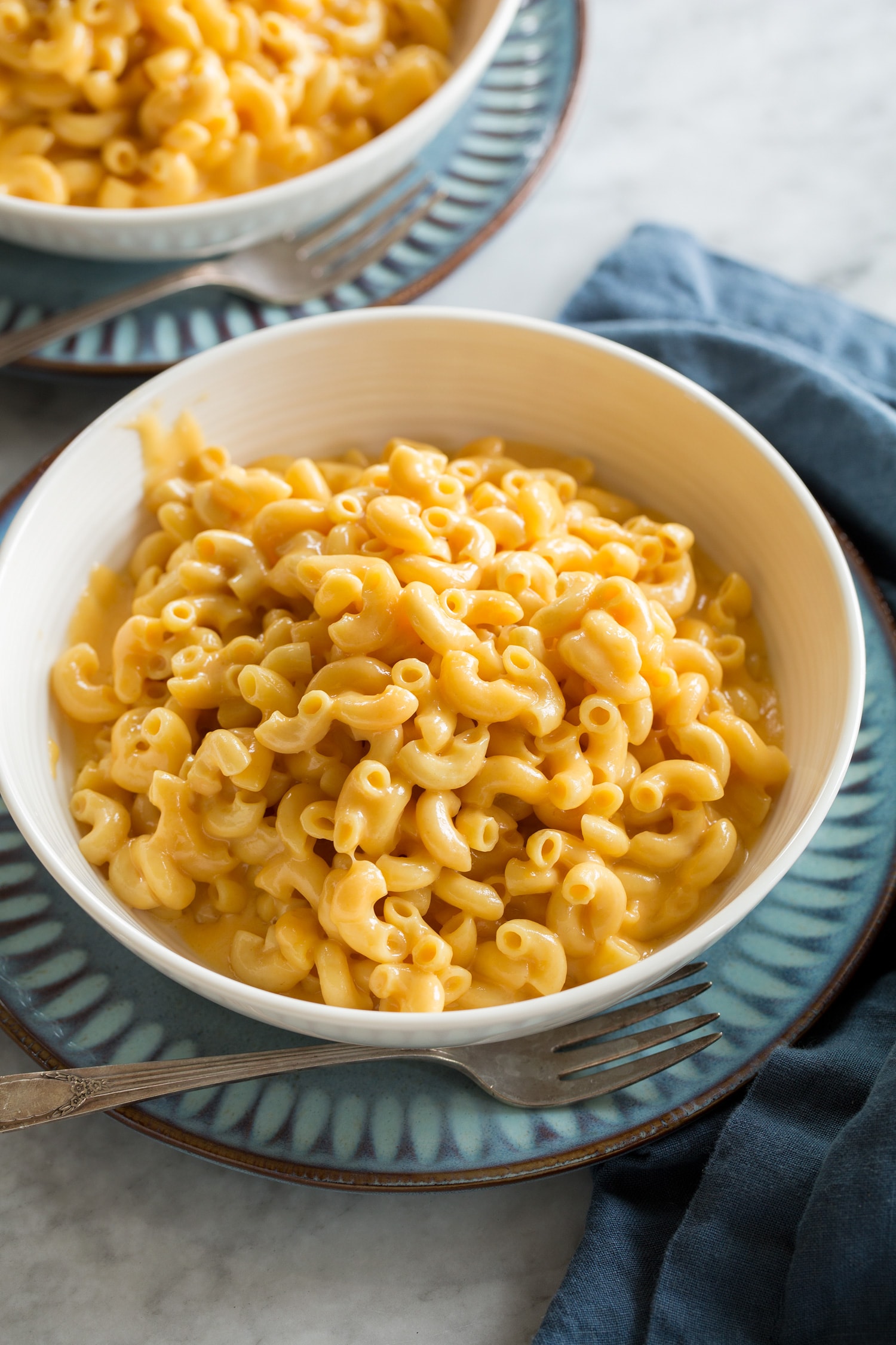 Crockpot Mac and Cheese Single serving of crockpot mac and cheese shown in a white soup bowl with a blue plate underneath.