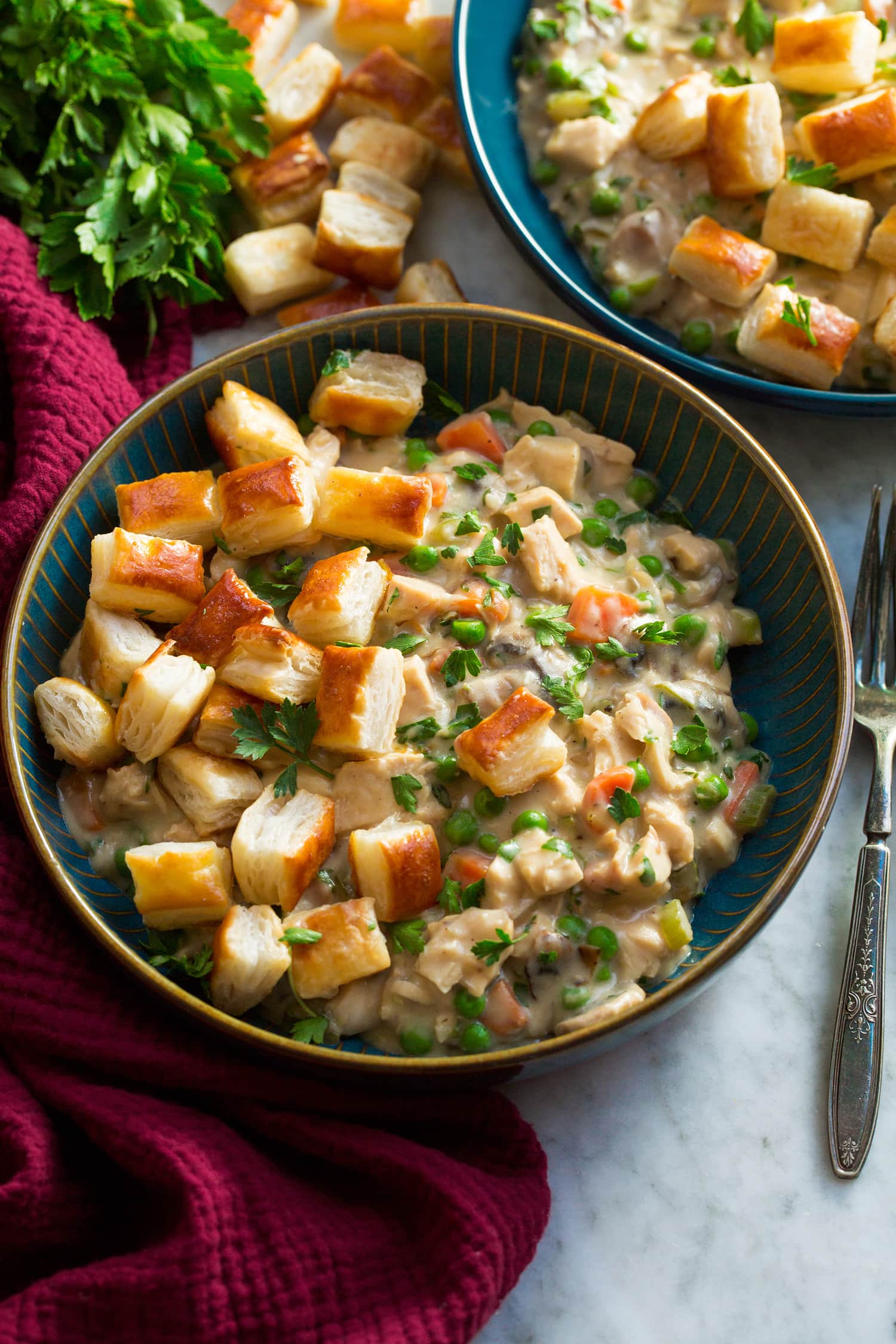 Chicken Pot Pie with Puff Pastry Chicken pot pie mixture in a blue bowl topped with puff pastry bites.