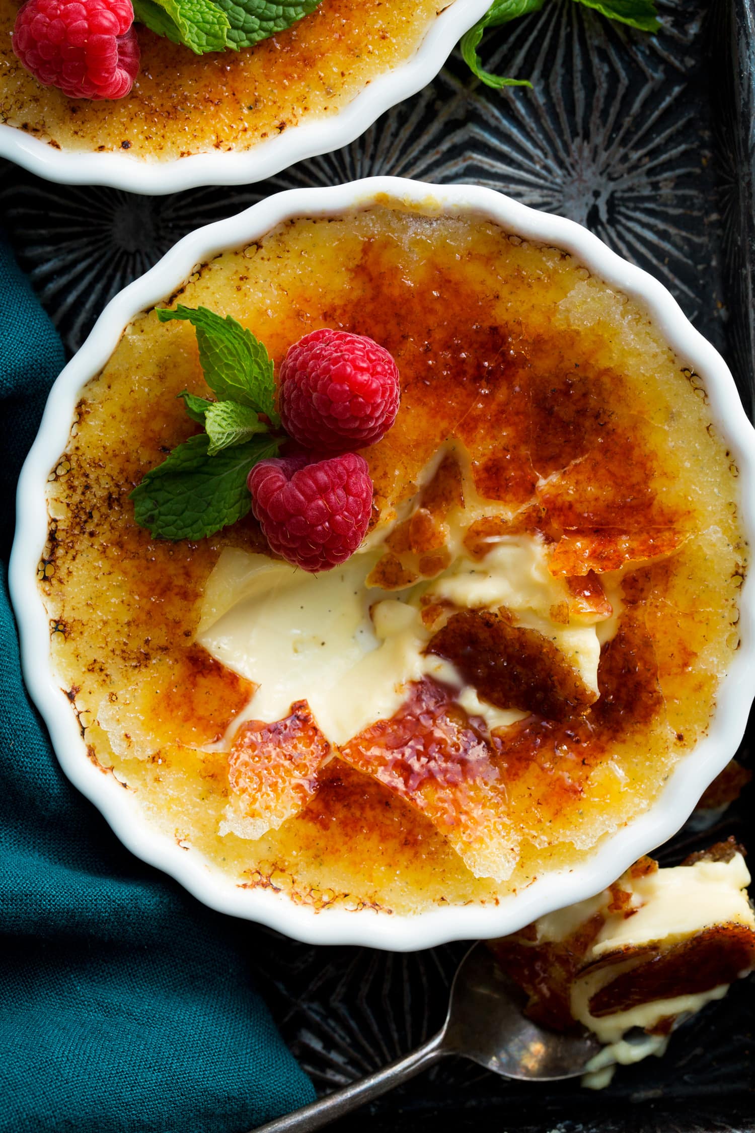 Creme Brûlée Close up photo of creme brûlée garnished with raspberry and mint.