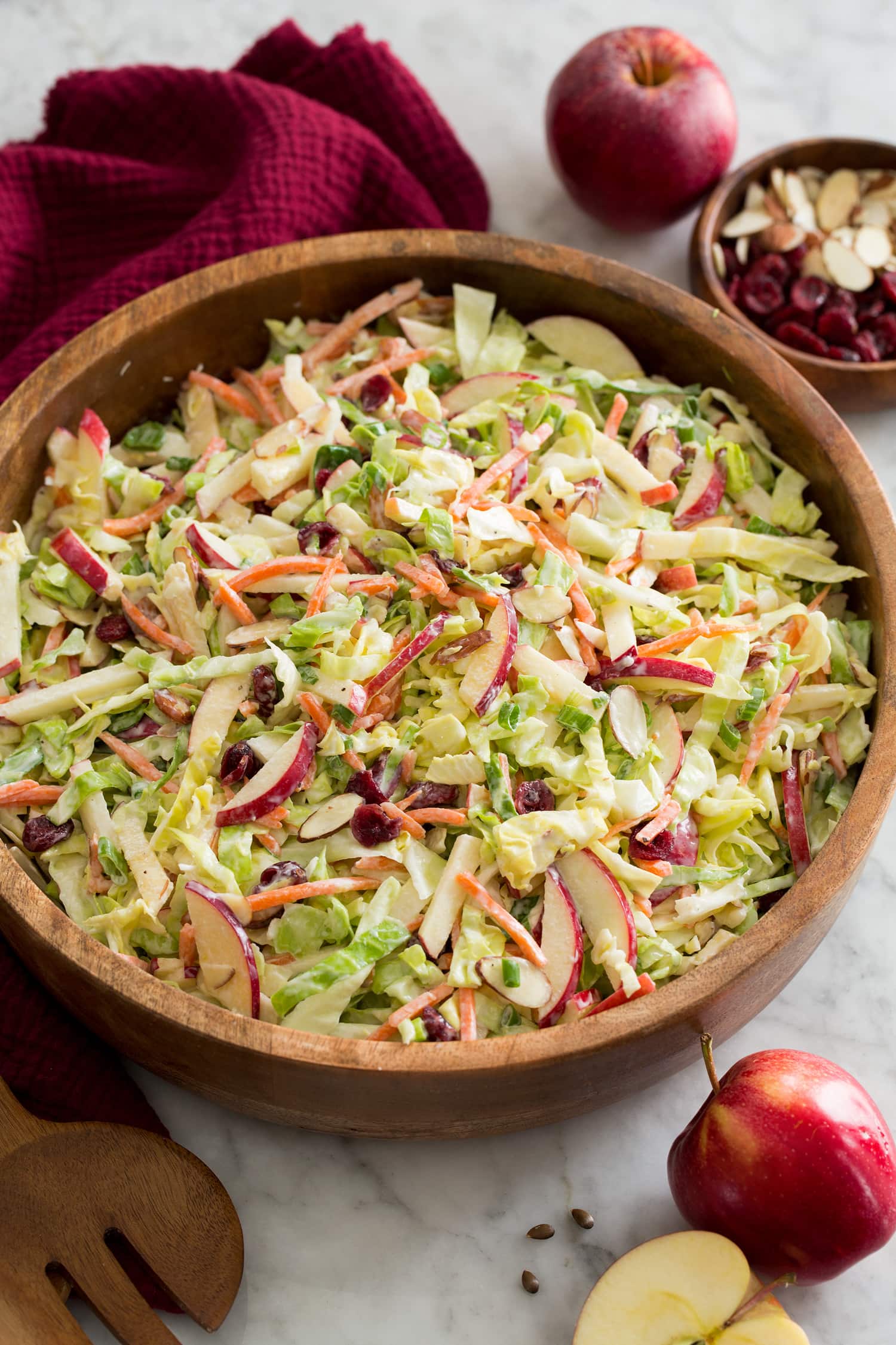 Apple Slaw Homemade apple slaw with shredded cabbage, apples, carrots, almonds and dressing shown in a wooden salad bowl.