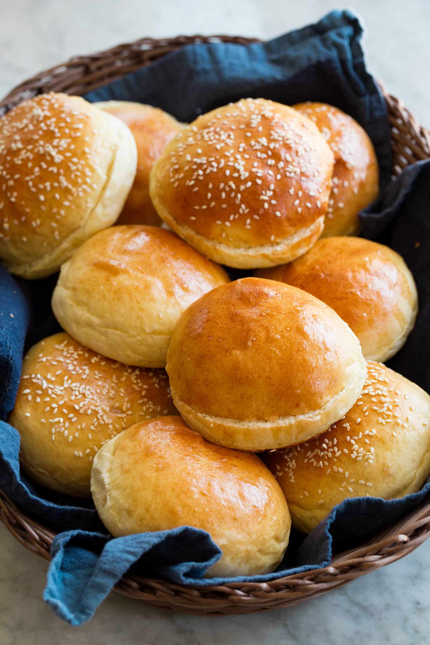 Homemade Hamburger Buns Homemade hamburger buns shown in a basket with a blue cloth.