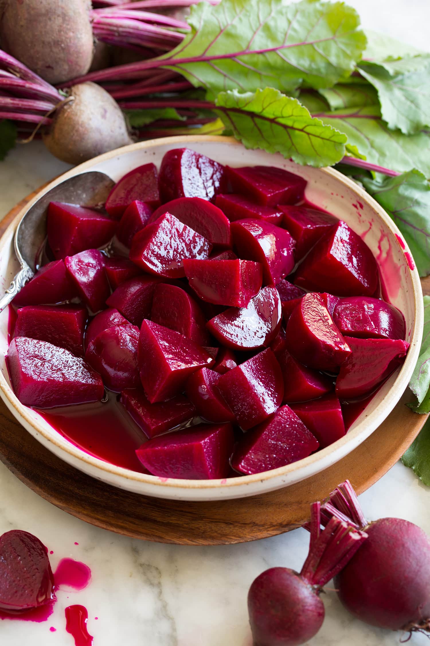 Pickled Beets {Easy Refrigerator Method} Chopped homemade pickled beets shown in a bowl surrounded by fresh beets.