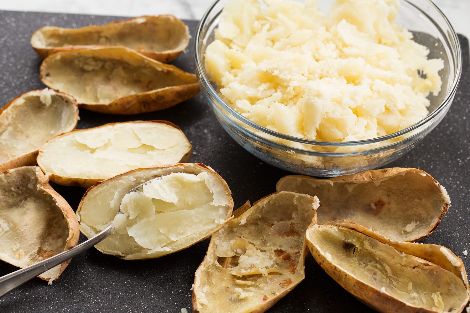 Baked Potato Soup Scooping out potato flesh from skins.