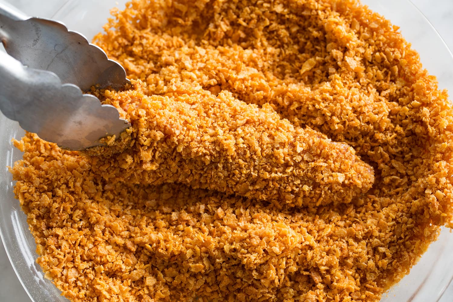 Hot Honey Chicken Covering chicken in crushed cornflakes.