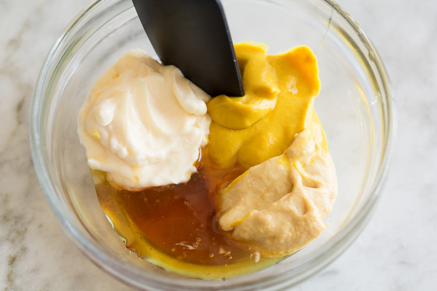 Ham and Cheese Sliders Making creamy honey mustard spread in glass mixing bowl.
