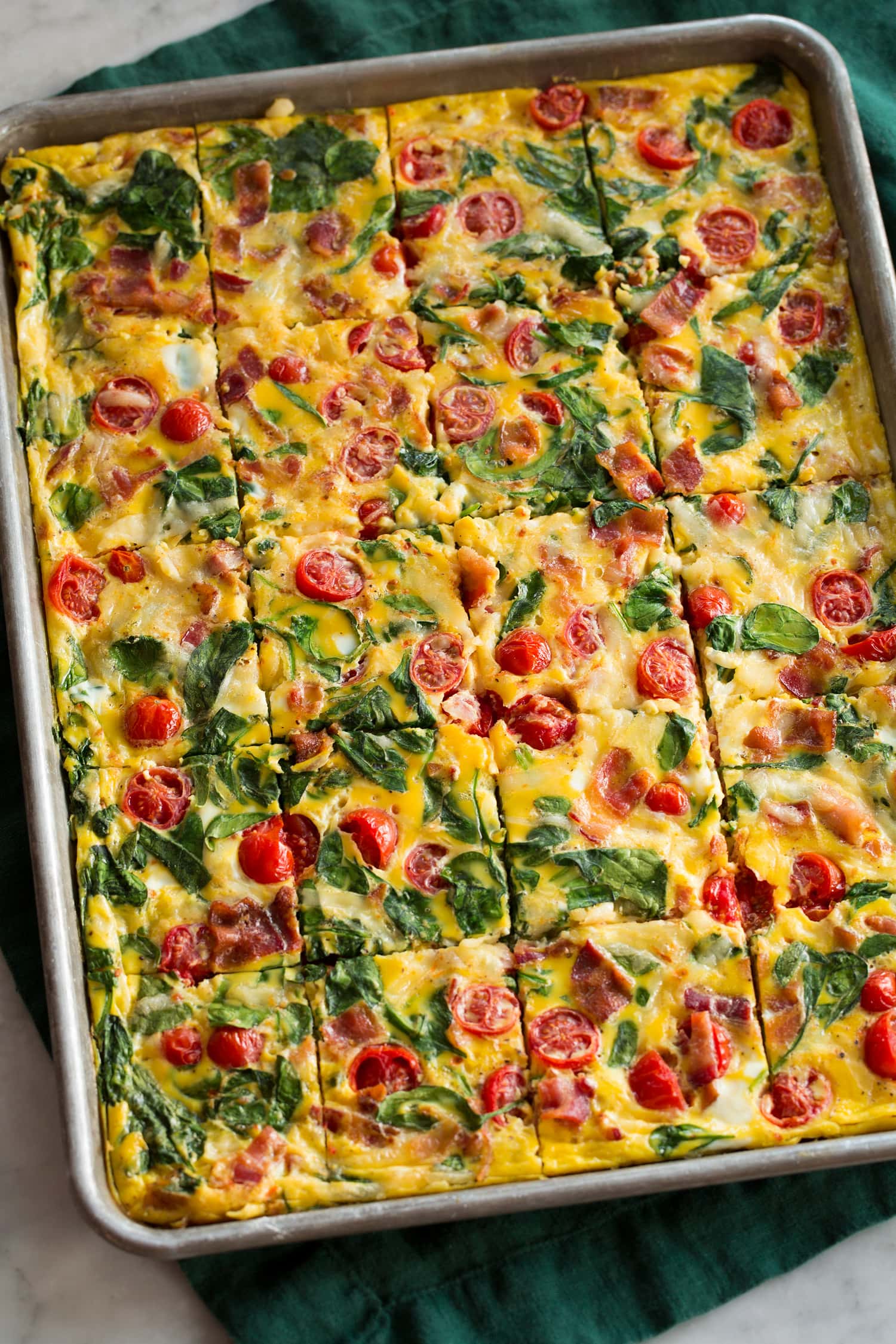 Sheet Pan Eggs Bacon, tomato, spinach eggs in a baking sheet.