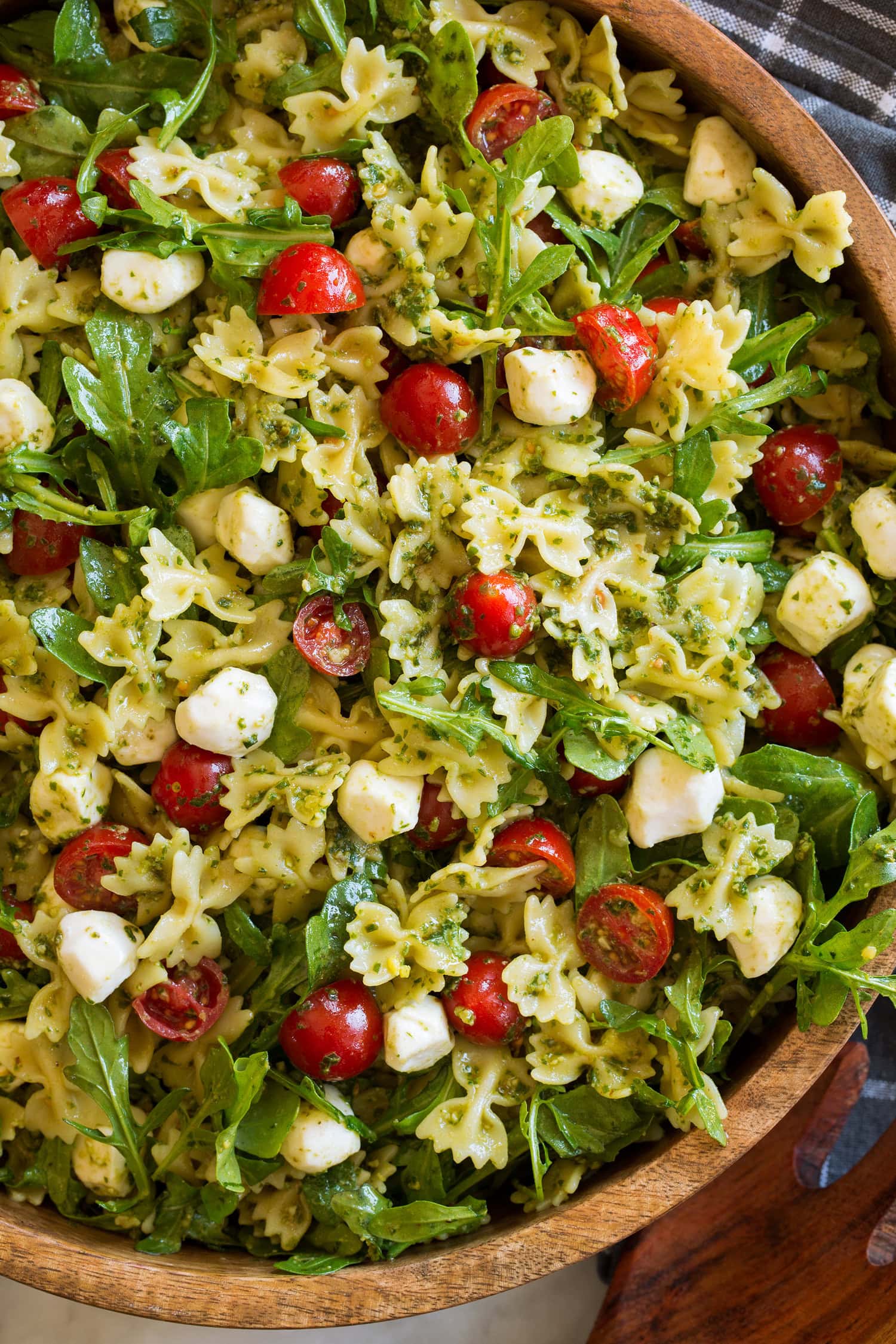 Pesto Pasta Salad Close up photo of bowtie pasta salad with pesto, tomatoes, arugula and fresh mozzarella.