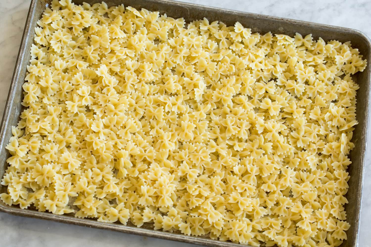 Pesto Pasta Salad Pasta cooling on a cookie sheet.