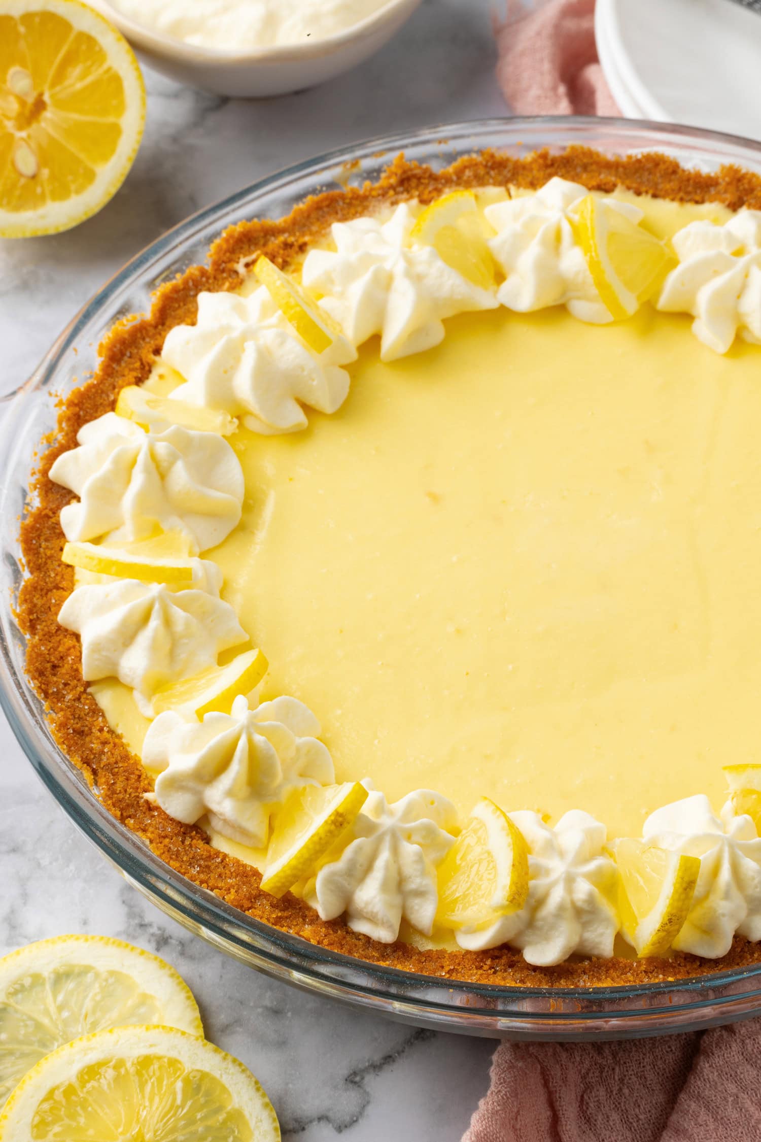 Lemon Icebox Pie Lemon icebox pie shown from a side angle up close. It's garnished with whipped cream swirls and lemon slices.