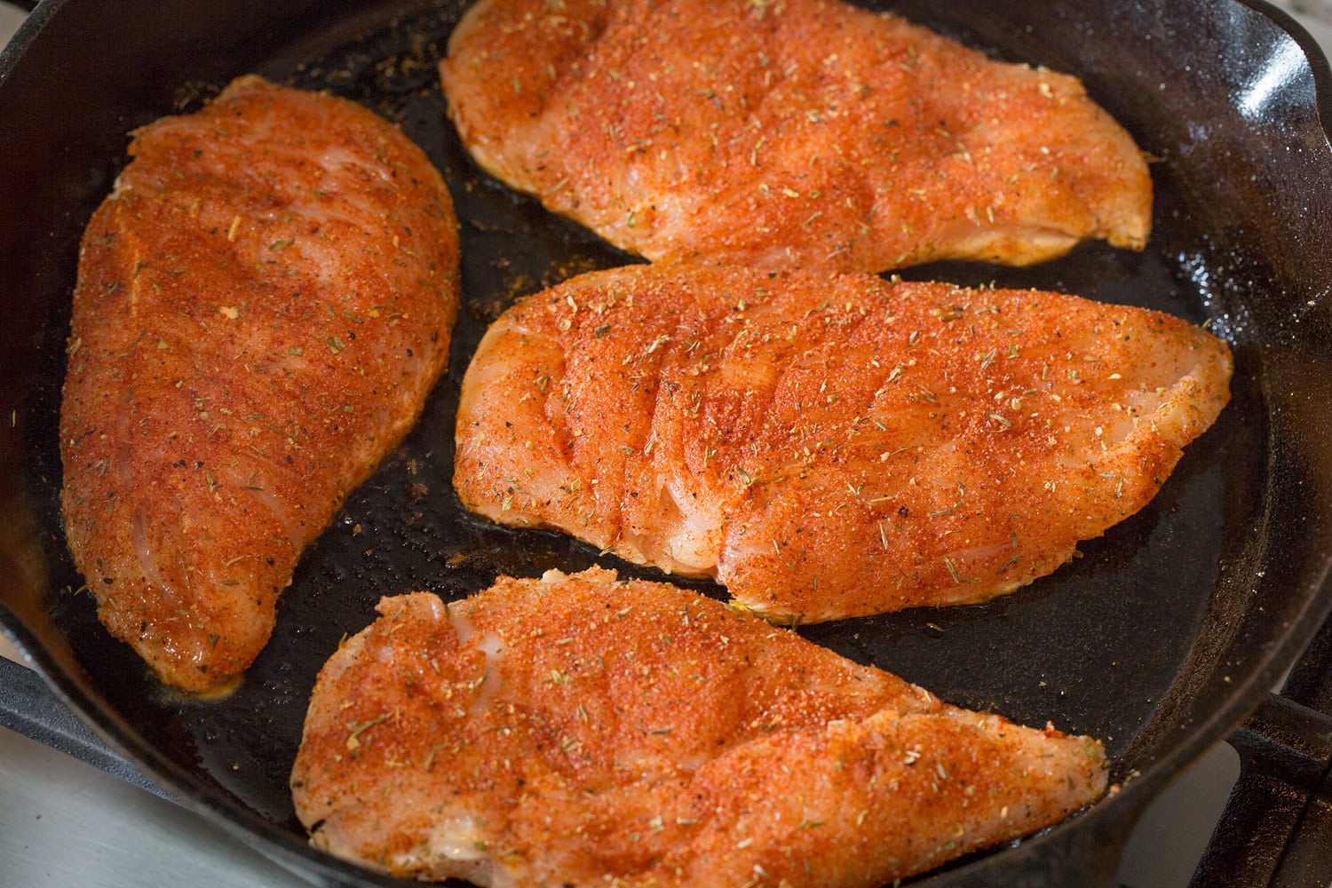 Blackened Chicken Chicken shown in skillet before cooking second side.