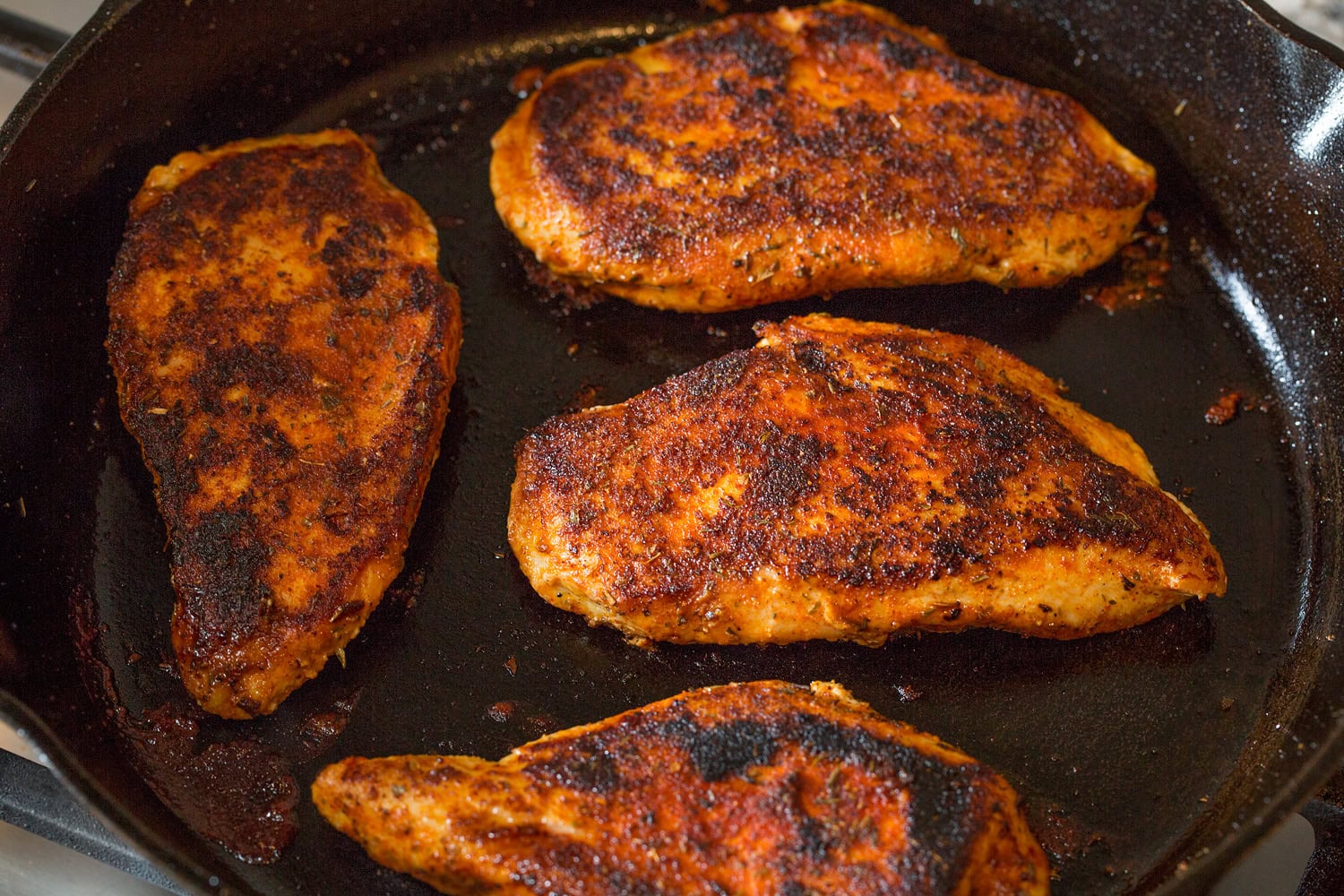 Blackened Chicken Blackened chicken in cast iron skillet with both sides cooked.