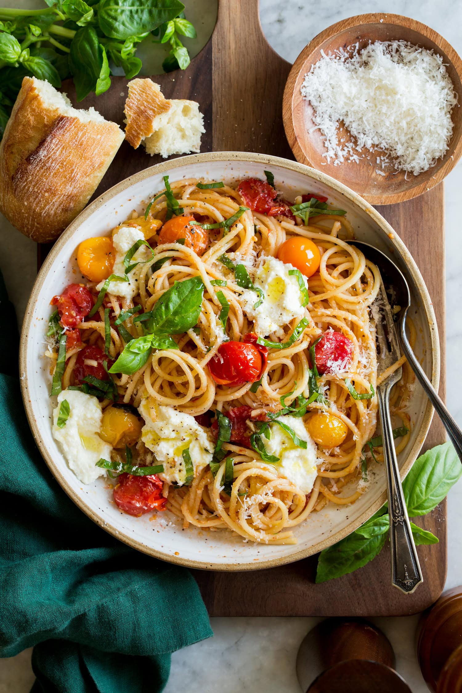 Cherry Tomato Pasta Cherry tomato pasta serving shown in a ceramic bowl with dollops of ricotta and grated parmesan on top.