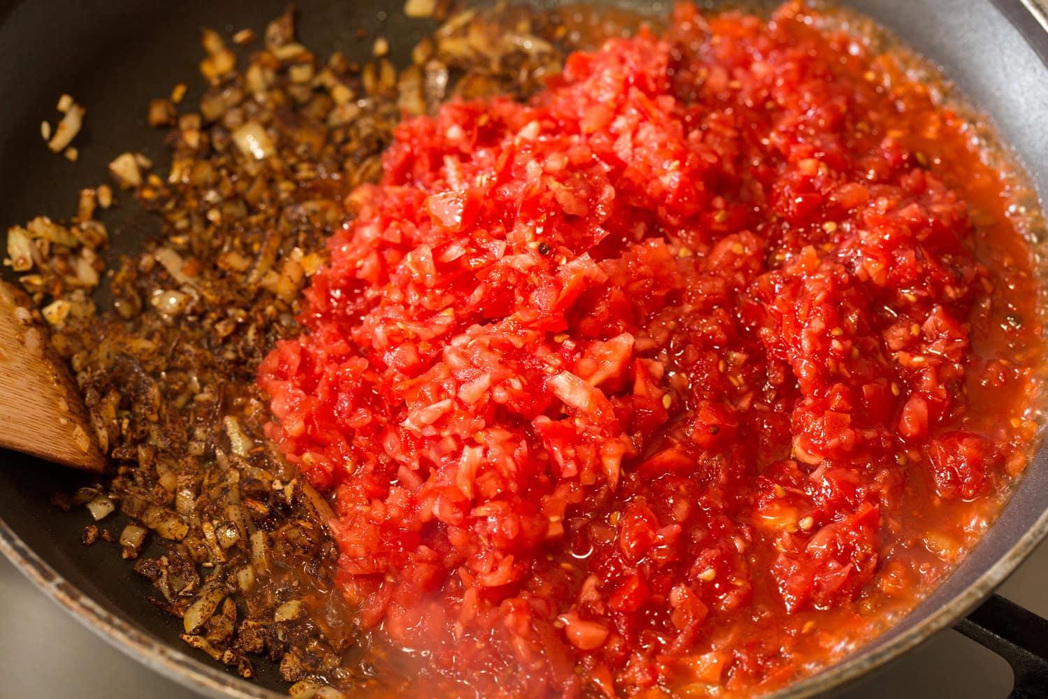Huevos Rancheros Minced tomatoes added to onion mixture in skillet.