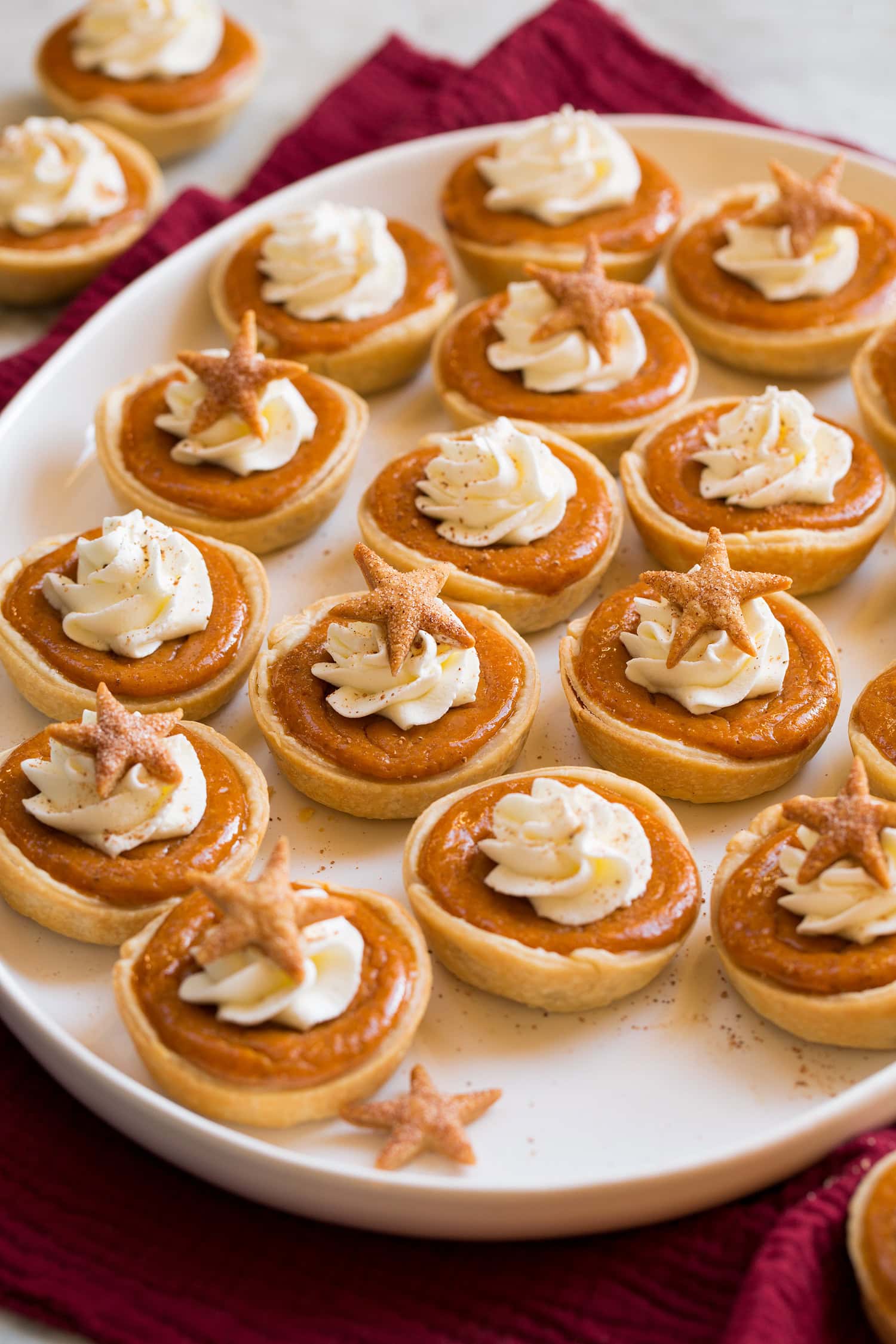 Mini Pumpkin Pies Platter filled with many mini pumpkin pies topped with whipped cream and cinnamon.
