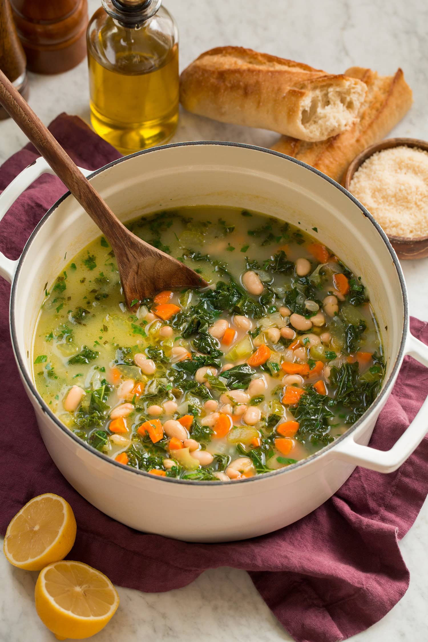 White Bean and Kale Soup Pot of white bean kale soup with baguettes shown to the side for serving.