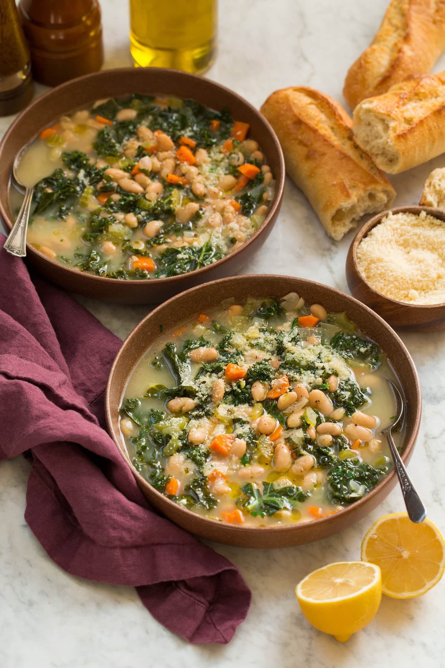 White Bean and Kale Soup Two bowls of white bean kale soup on a purple cloth.