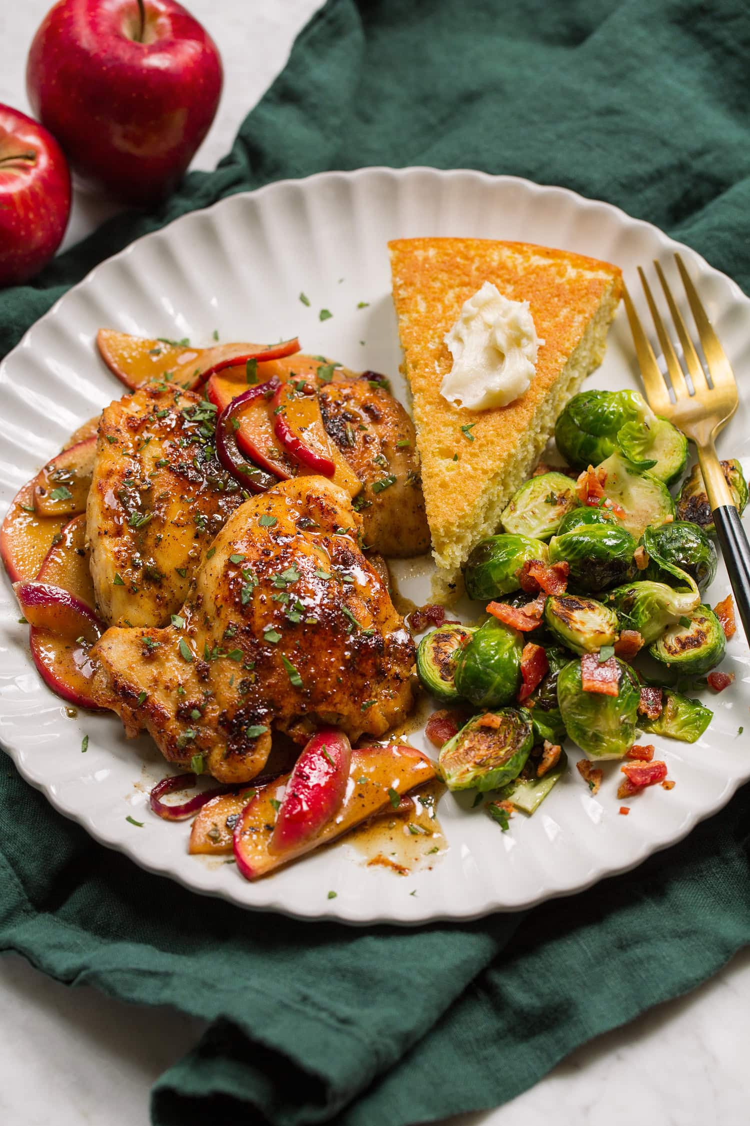 Apple Chicken Chicken thighs and apples served with cornbread and brussels sprouts.