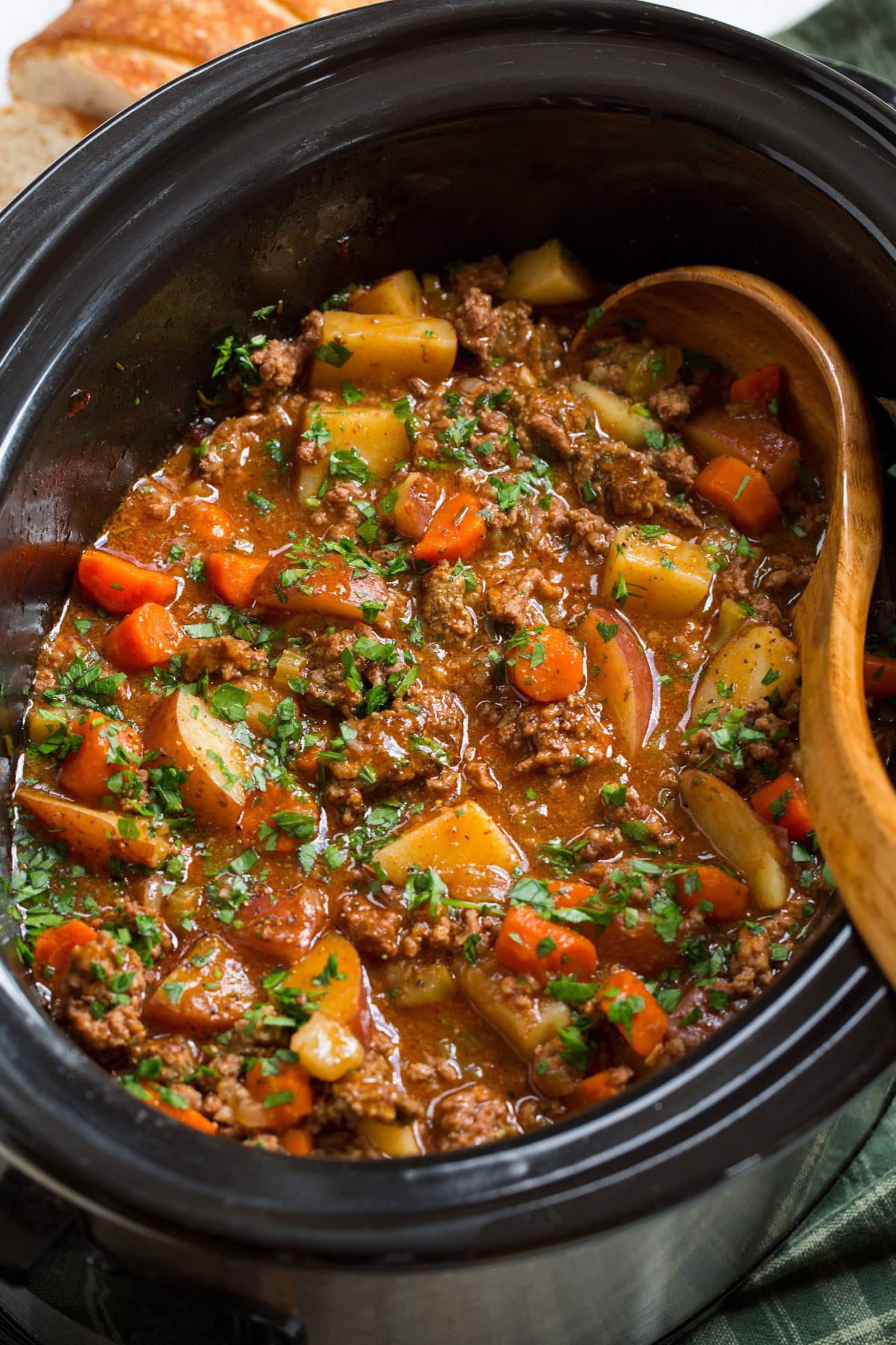 Ground beef stew with potatoes and carrots in a slow cooker.