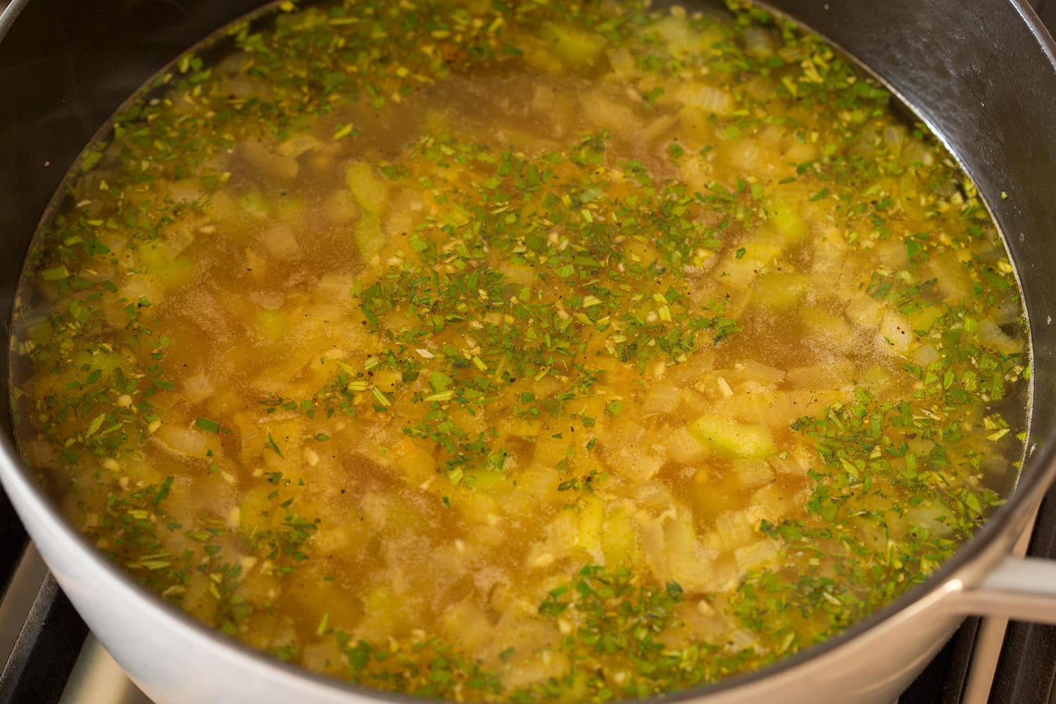 Turkey Soup Turkey stock and herbs added to vegetables in pot, simmering.