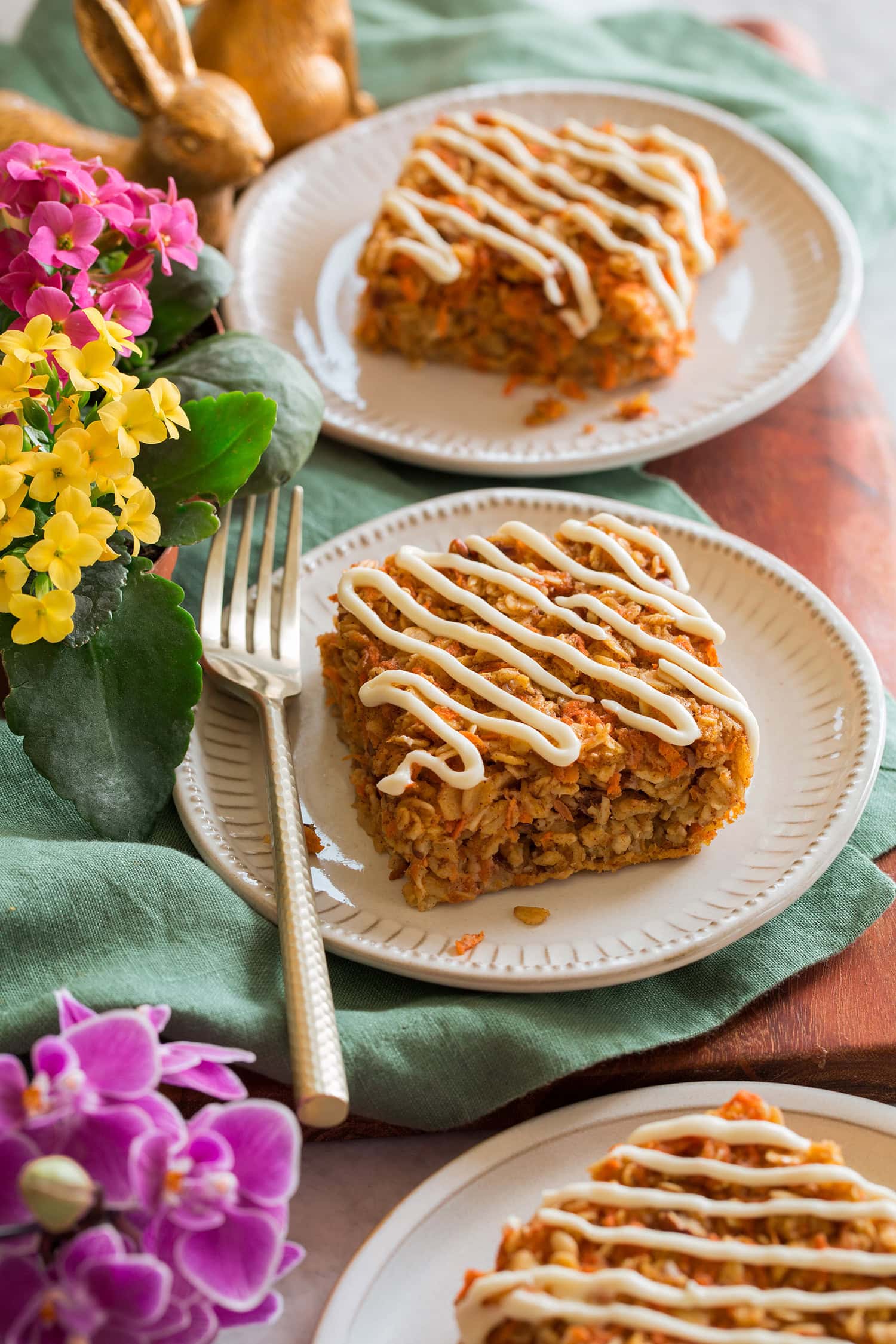 Two slices of carrot cake baked oatmeal covered in a cream cheese icing.